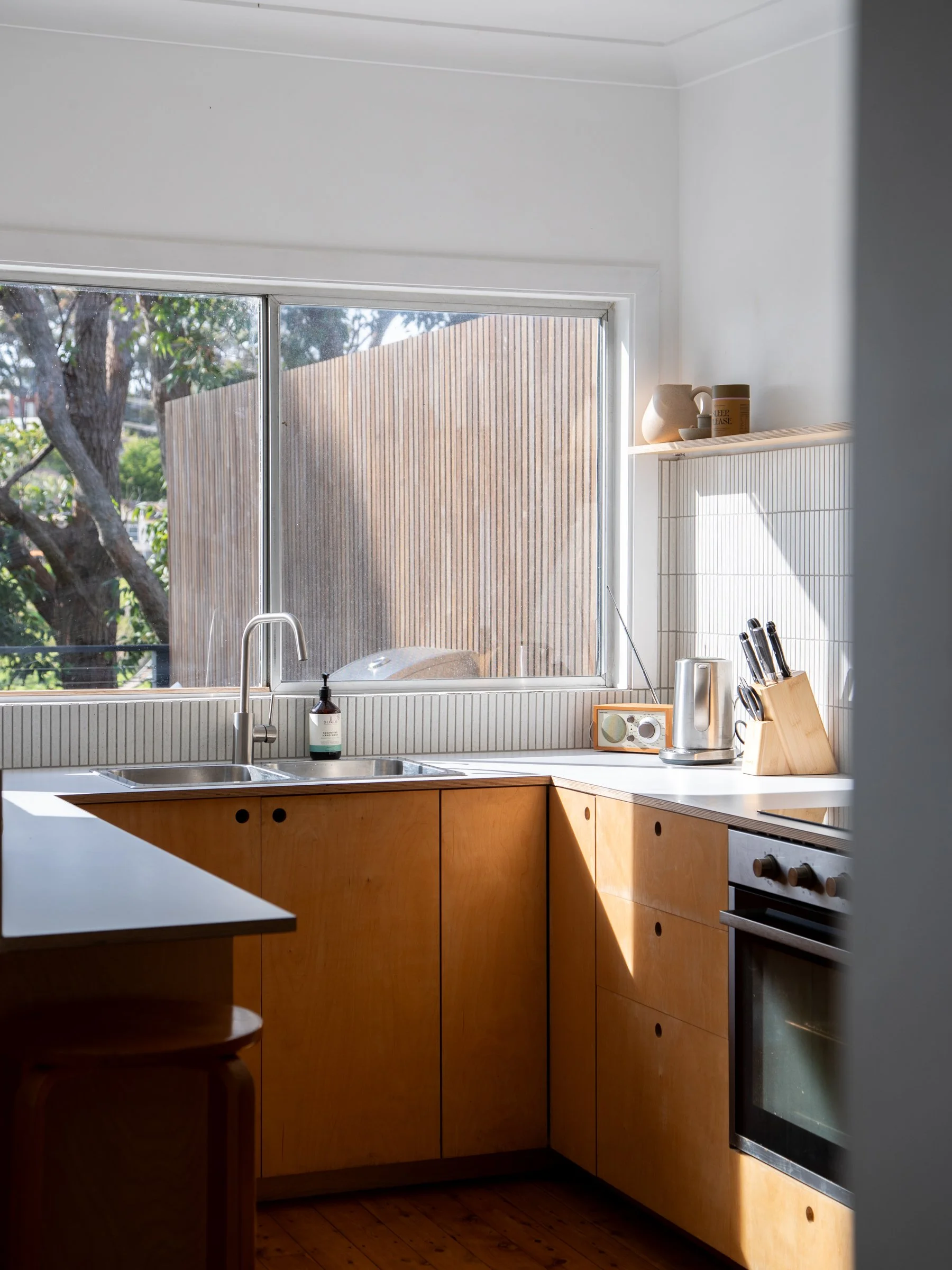Kitchen with a large window, wooden cabinets, a sink, countertop appliances, and utensils.
