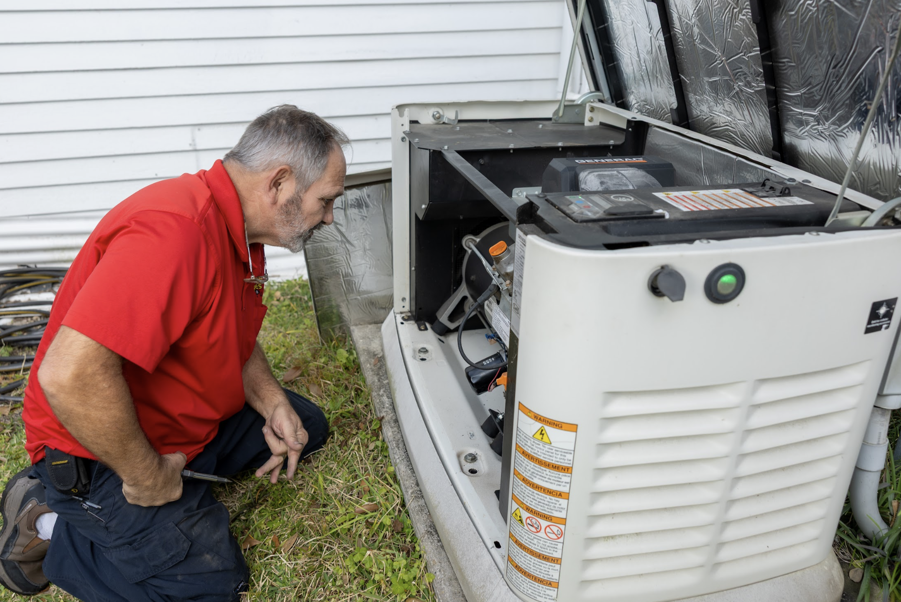 Technician inspecting an outdoor air conditioning unit near a white building.