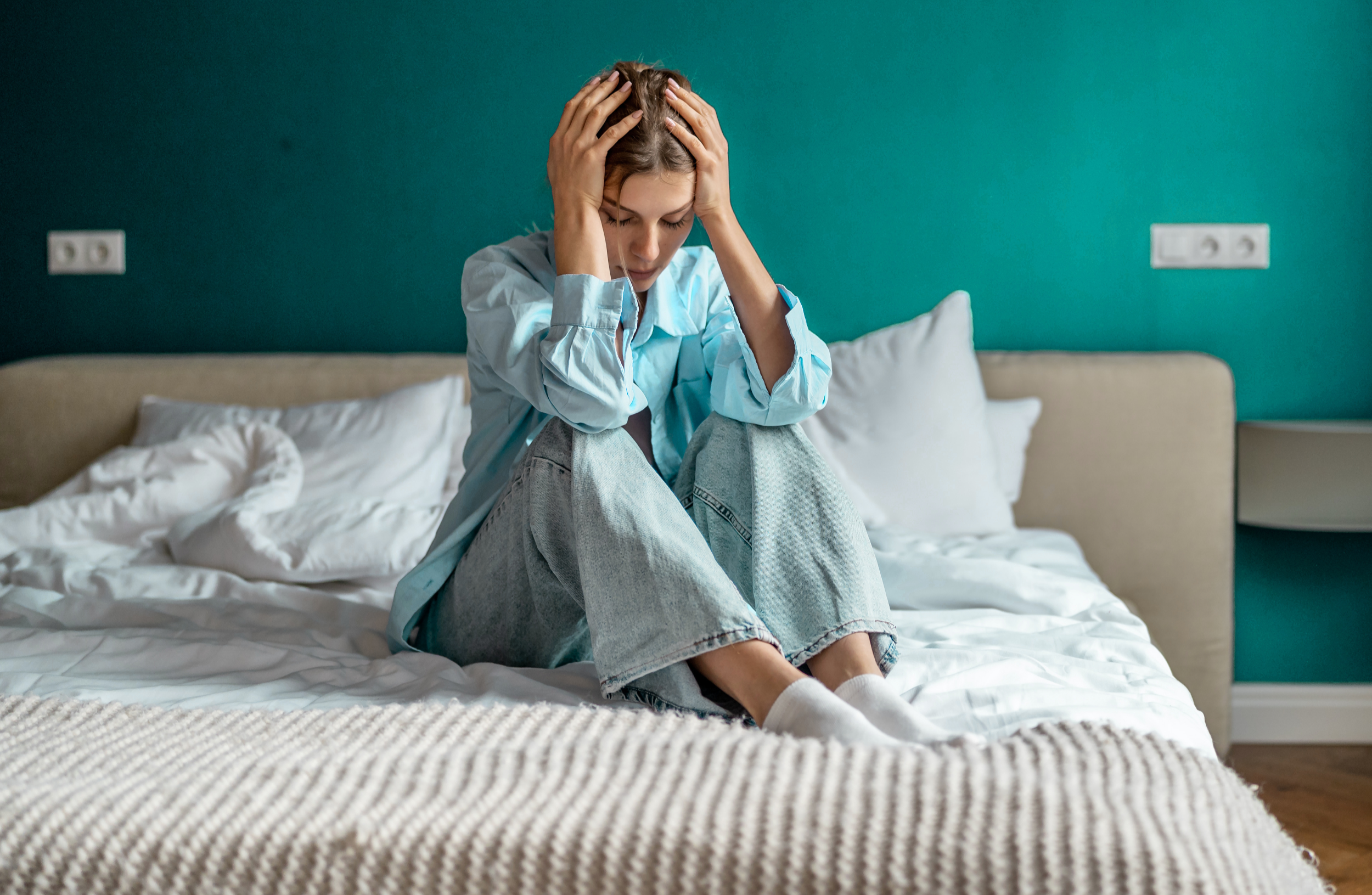 A woman sitting on the edge of a bed with her head in her hands