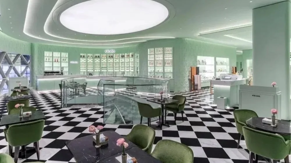 Iconic Prada Cafe Singapore with stunning curved architecture black and white checkered floor, green chairs, and mint green walls and ceiling.