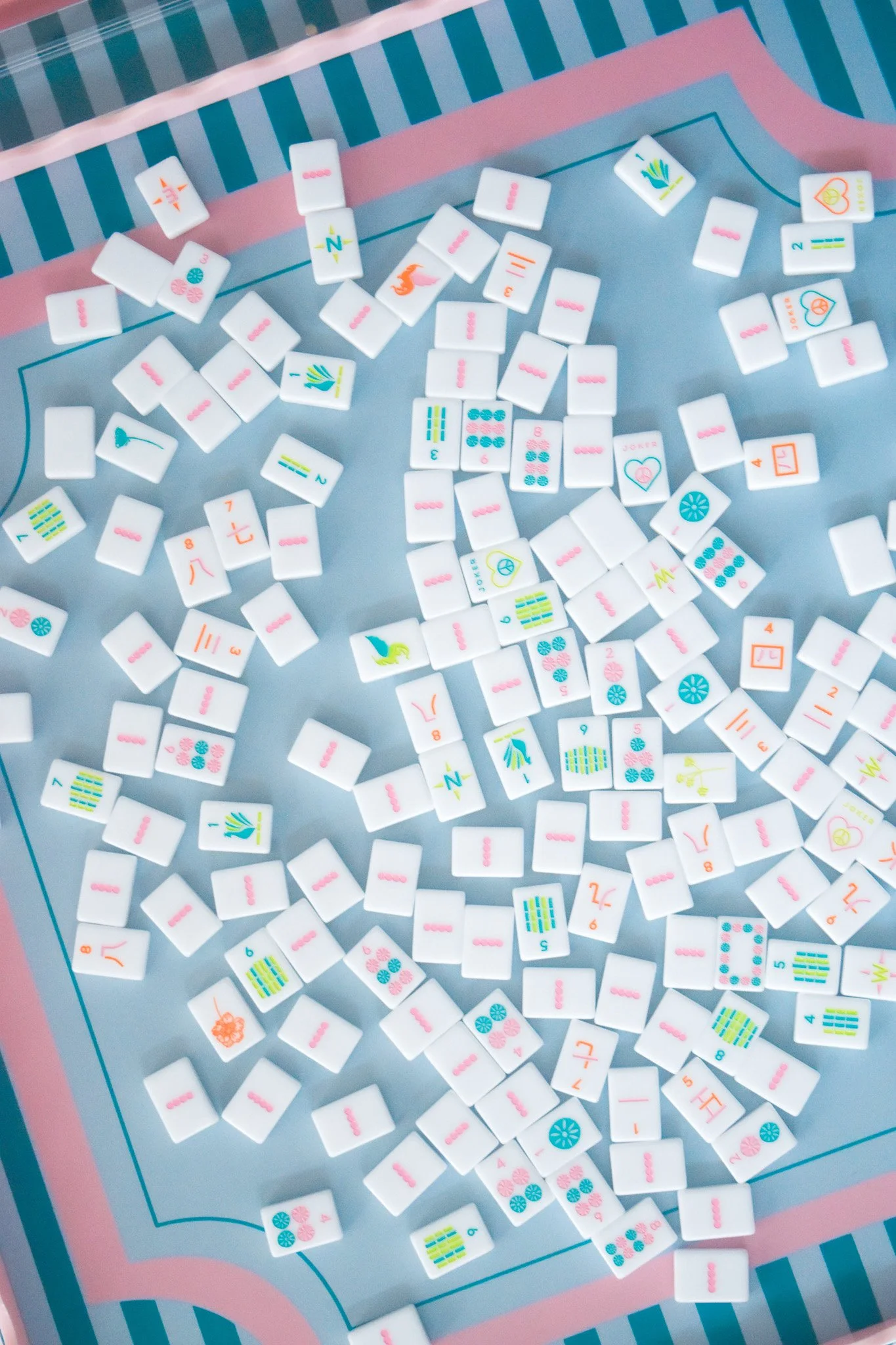 A pile of Mahjong tiles on a game board with colorful designs and symbols.
