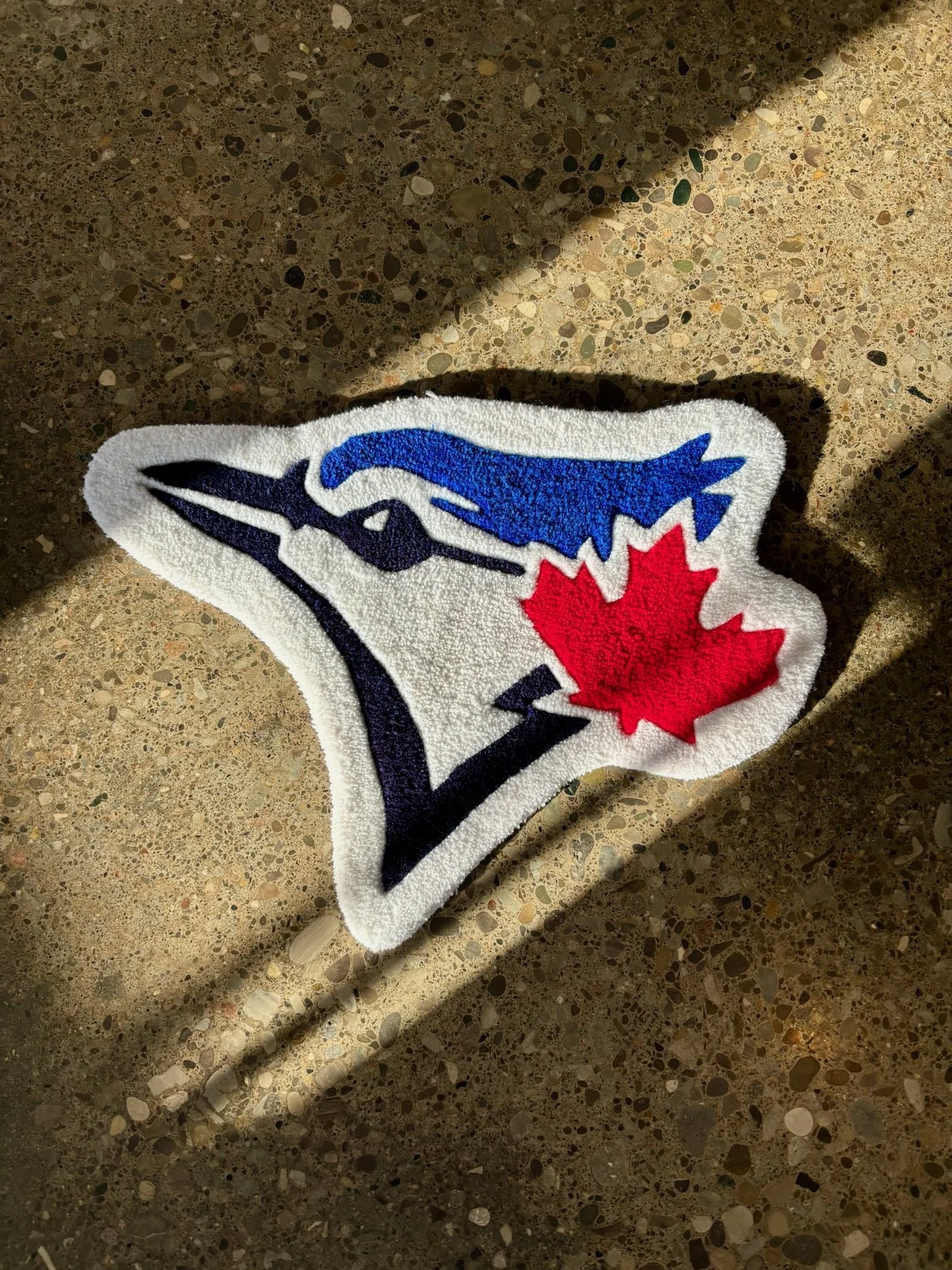 A speckled countertop with a Toronto Blue Jays patch featuring a blue jay bird and a red maple leaf.