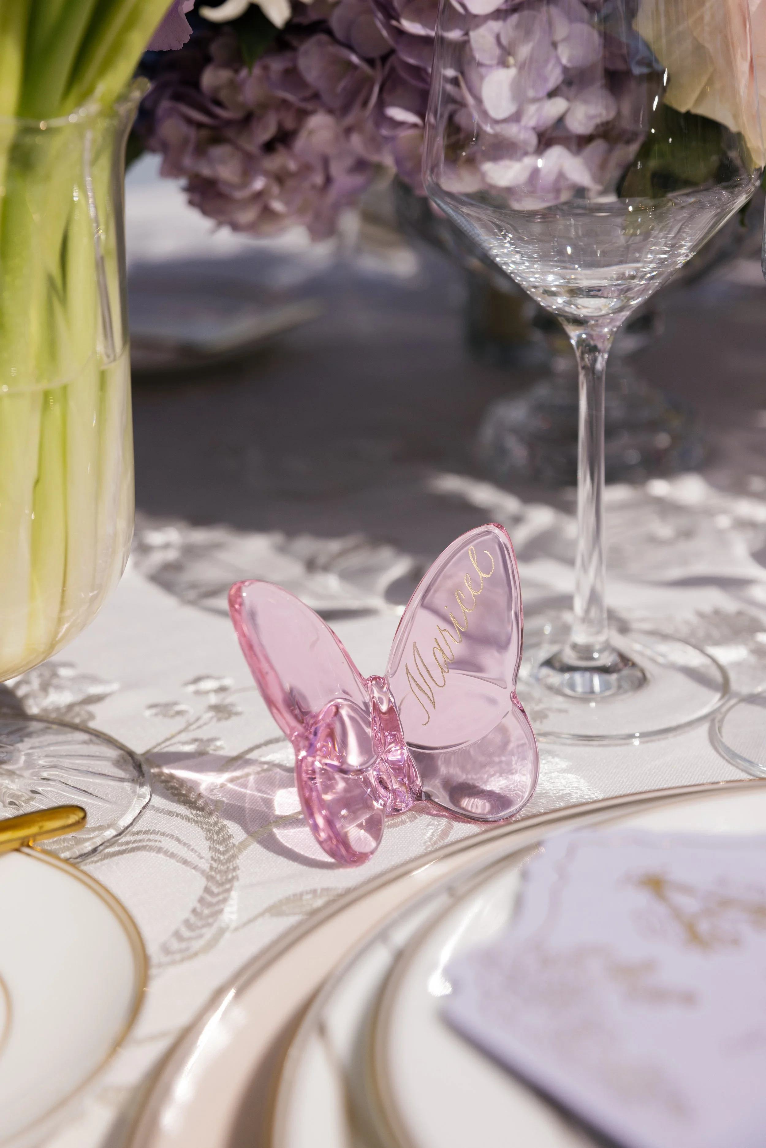 Pink glass butterfly place card personalized with Married in gold calligraphy at a wedding reception.