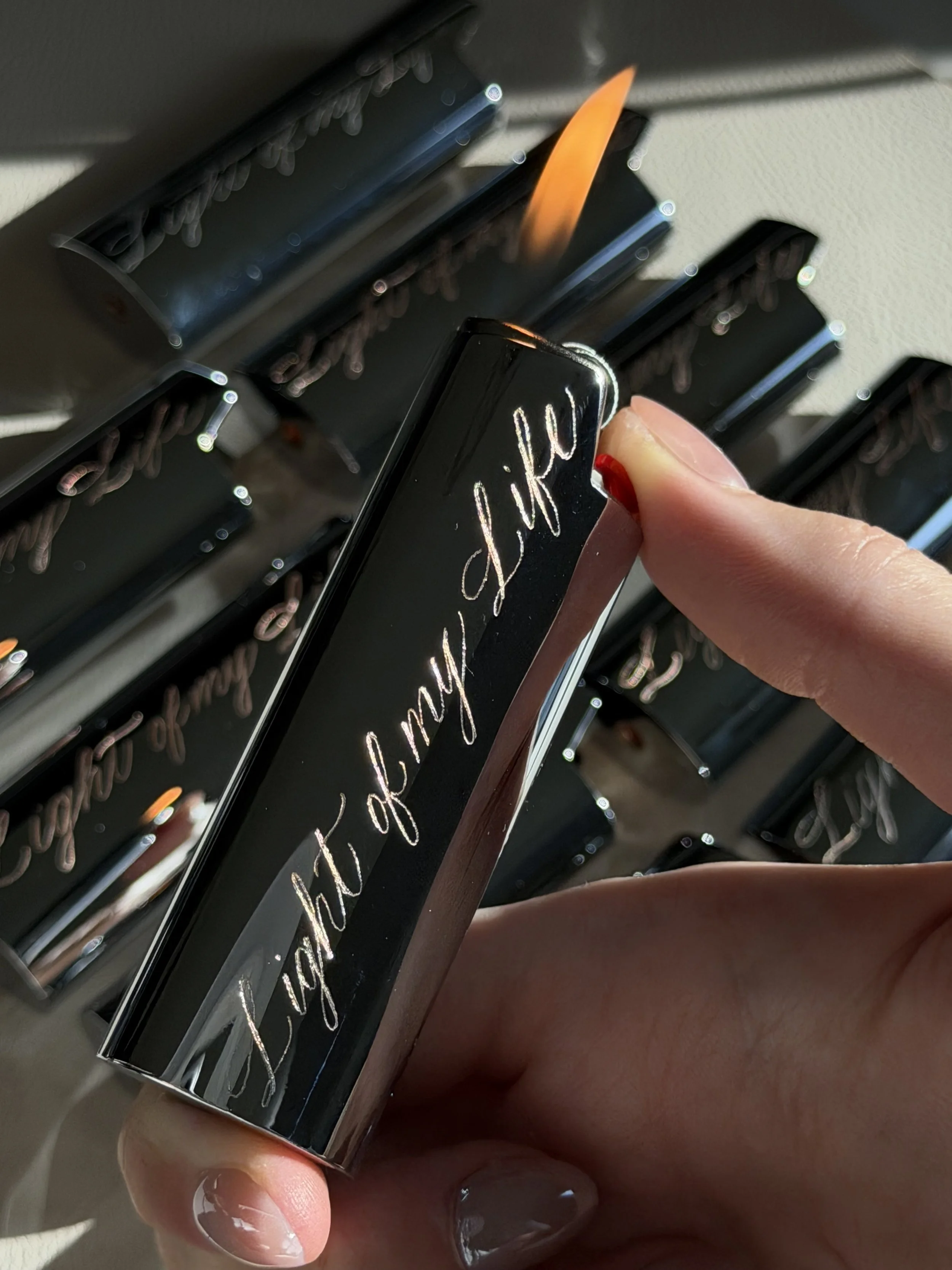 Custom engraved black lighter cases with cursive lettering for an engagement party.