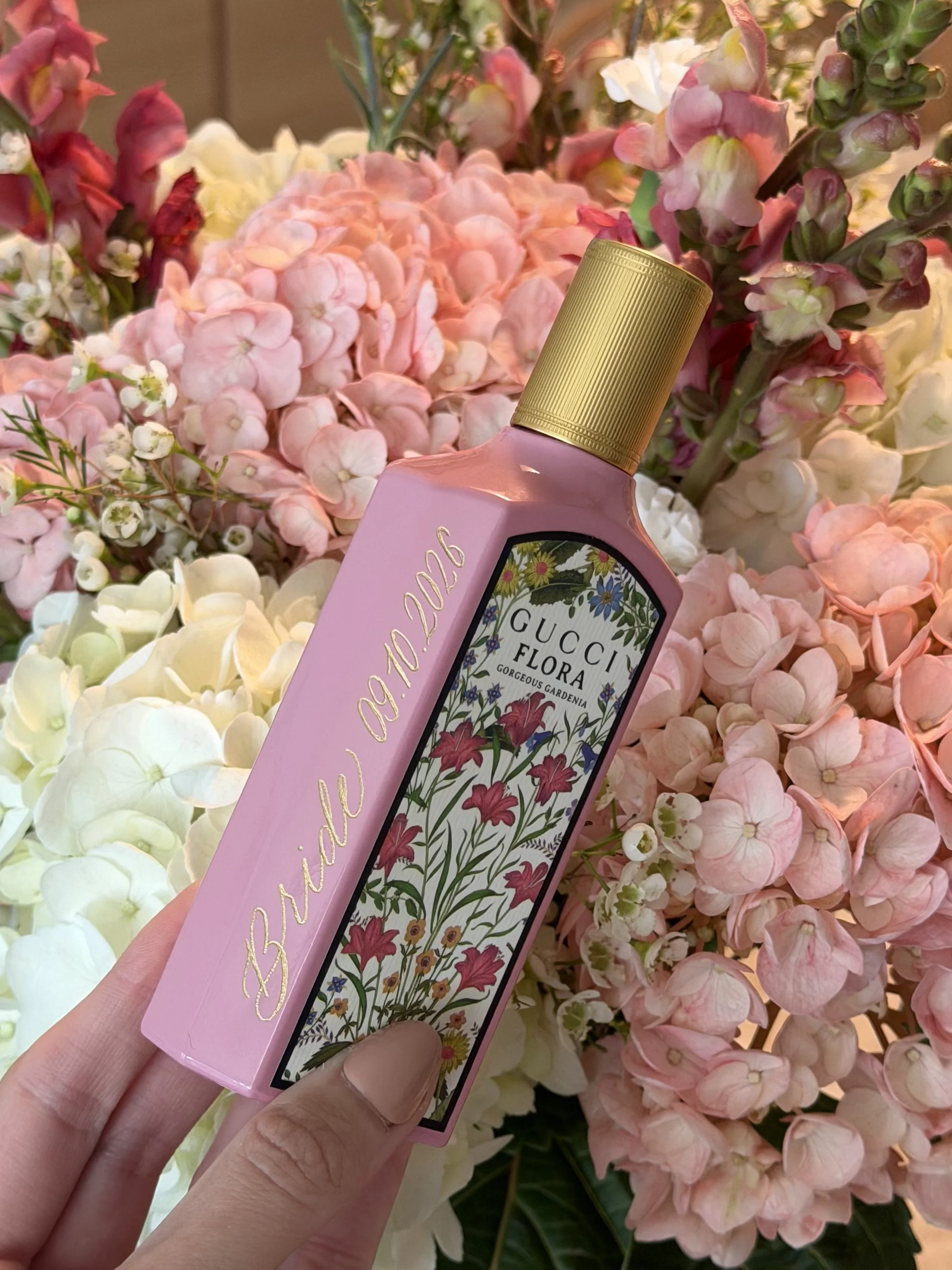 Personalized Gucci Flora fragrance bottle with hand engraving, styled with pink hydrangeas.