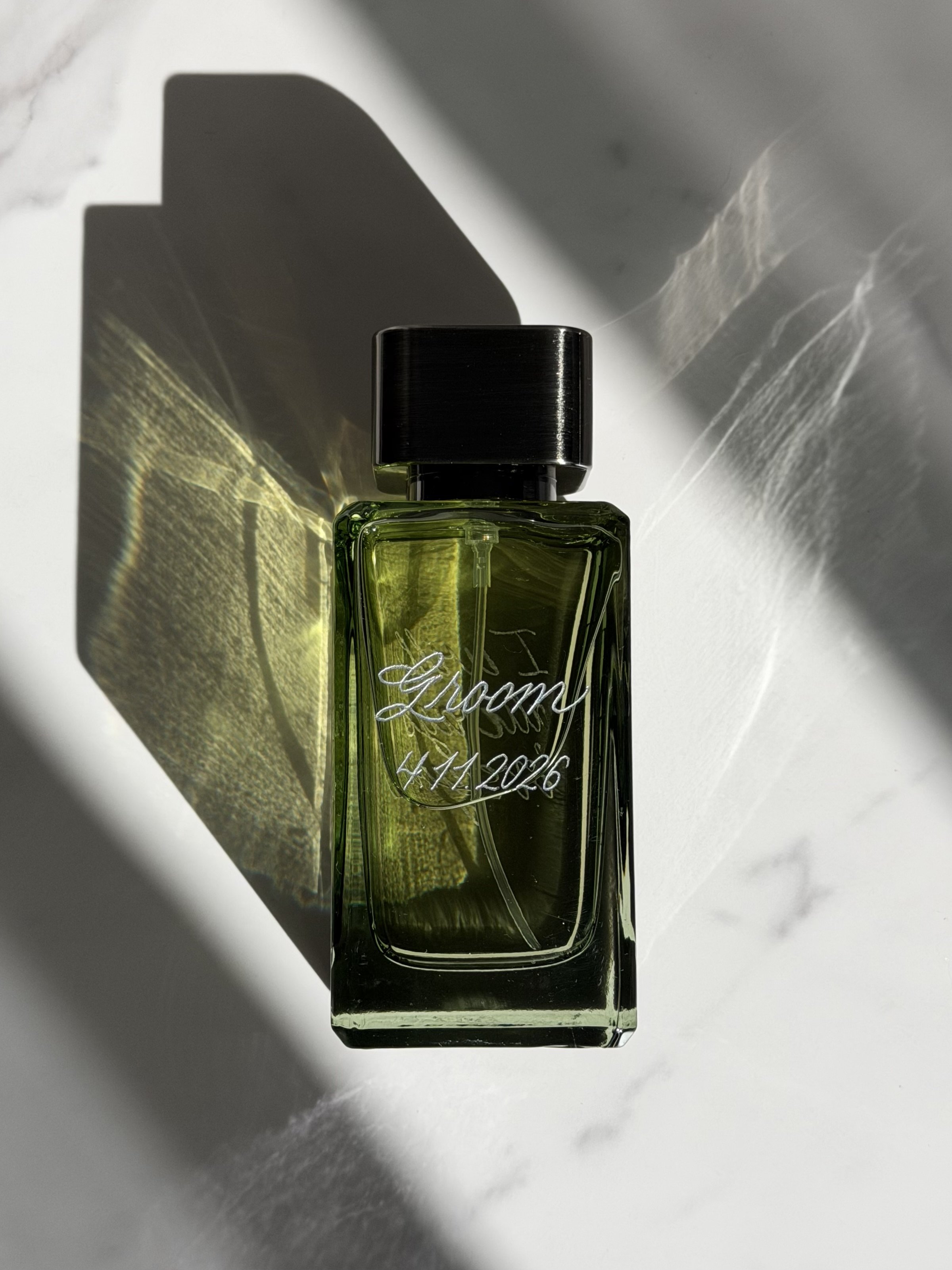 Green fragrance bottle personalized with custom hand engraving and a wedding date.