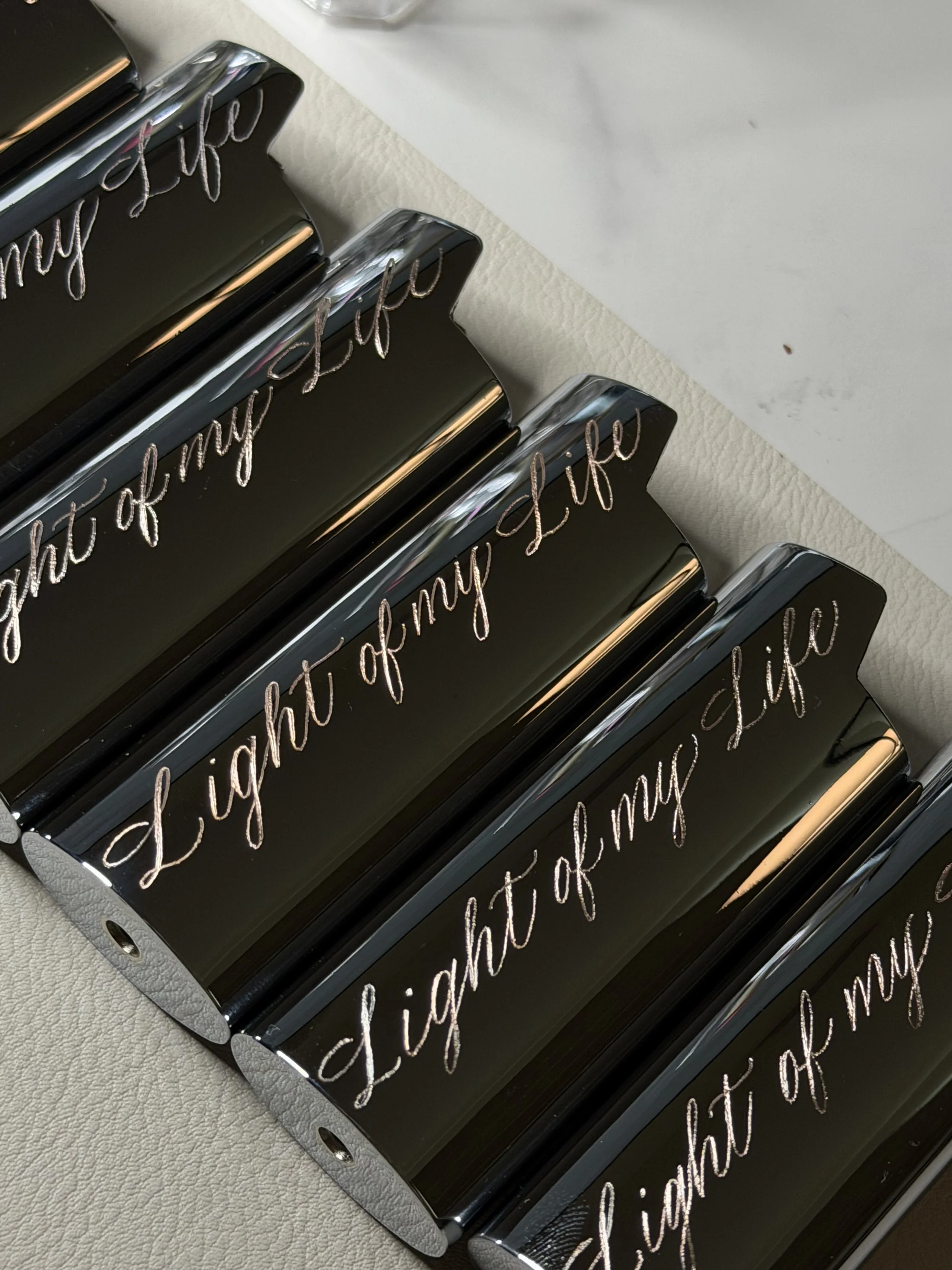 Custom engraved black lighter cases with “Light of My Life” in cursive lettering.