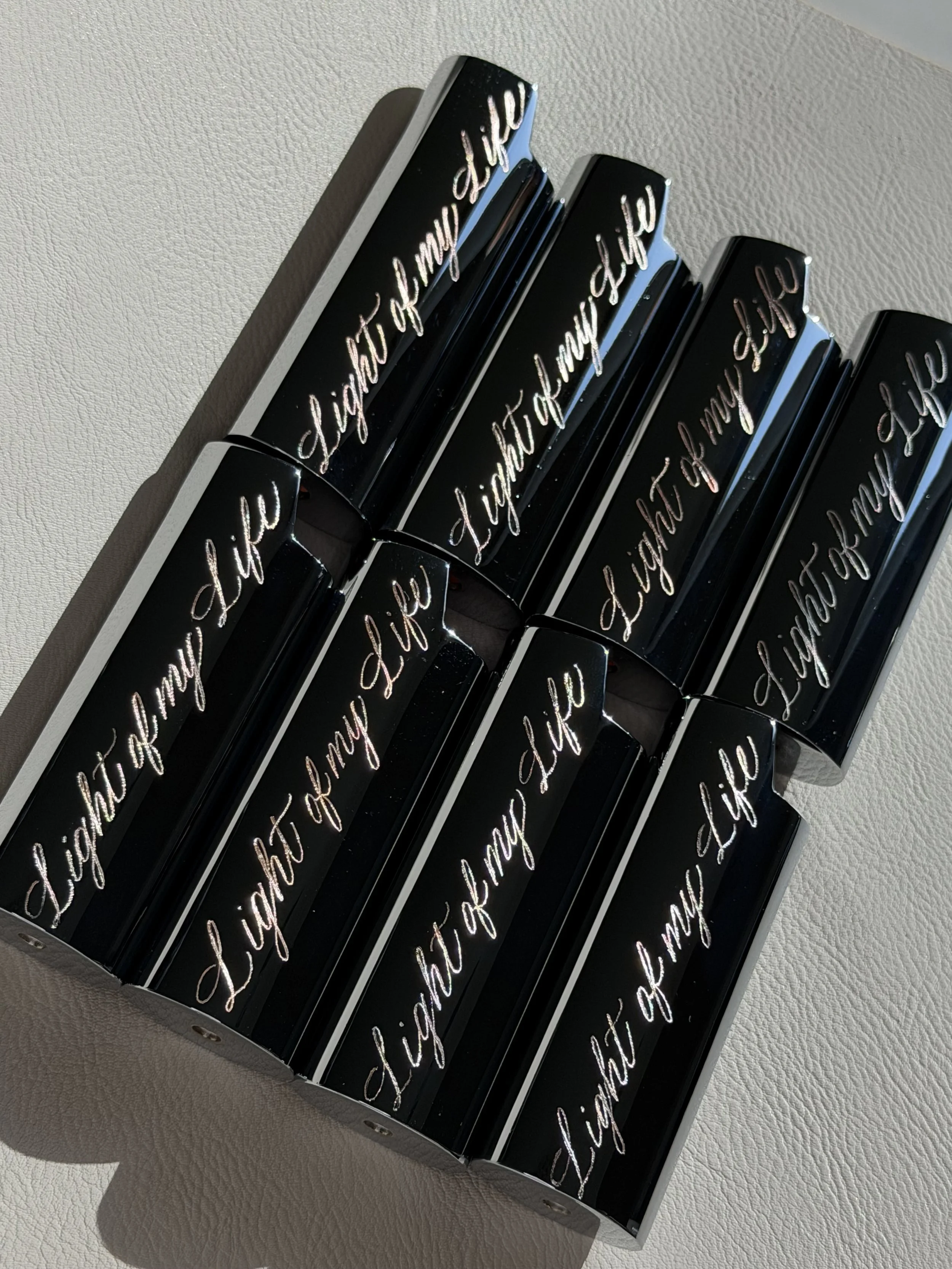 Custom engraved black lighter cases with “Light of My Life” in cursive lettering.