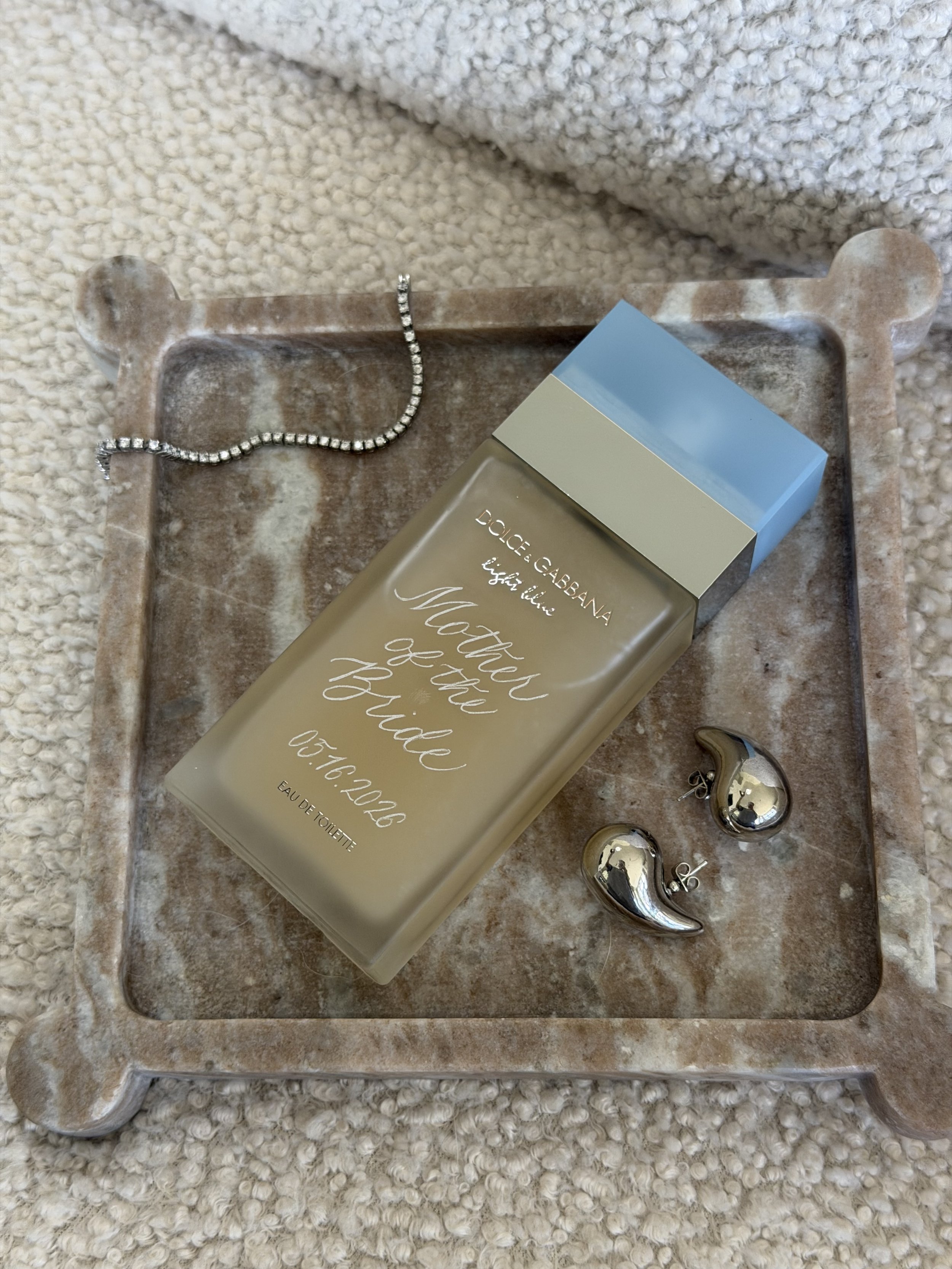 Dolce & Gabbana fragrance bottle personalized with custom hand engraving, styled with silver jewelry.