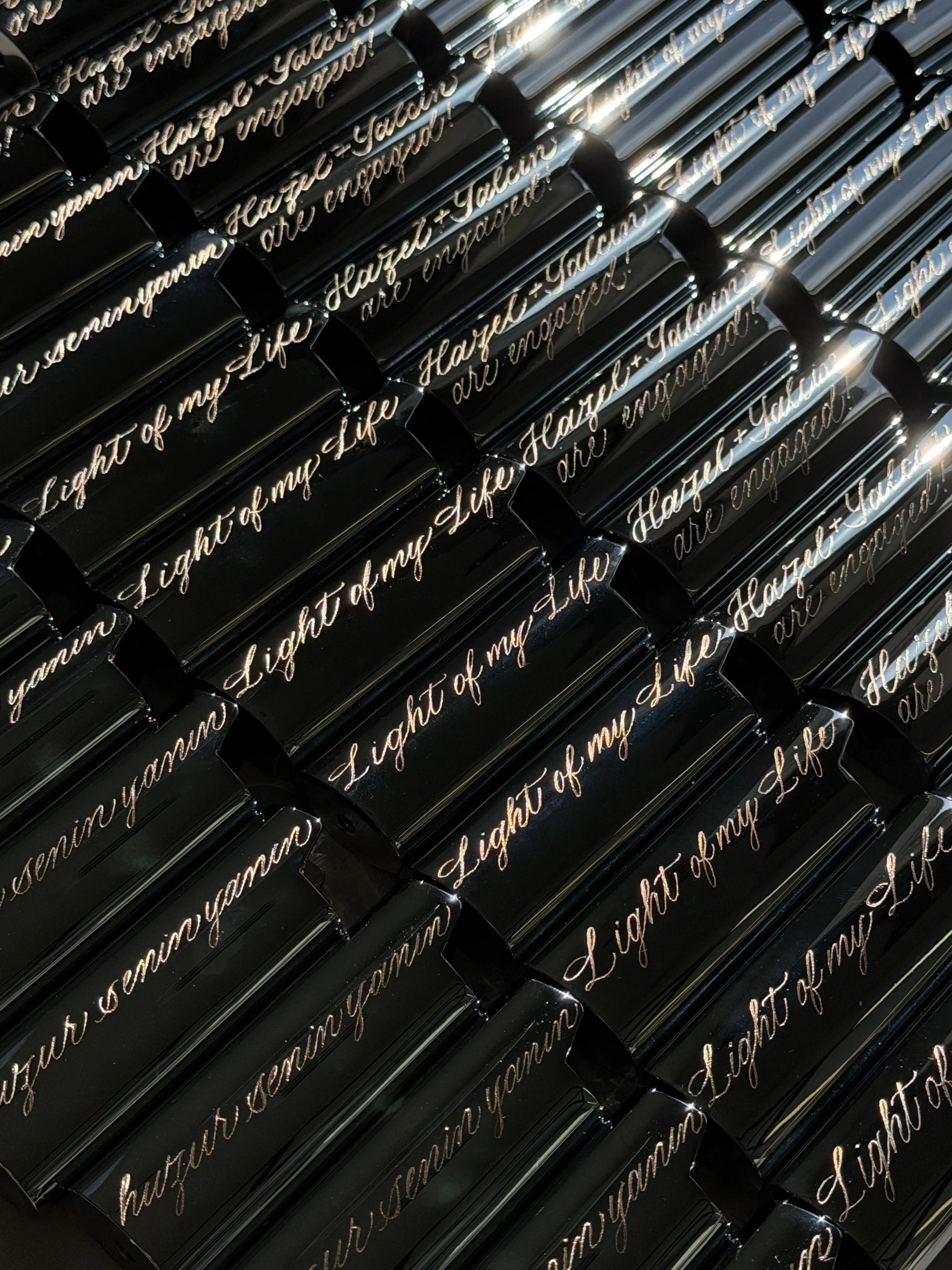 Custom engraved black lighter cases with cursive phrases for an engagement party.