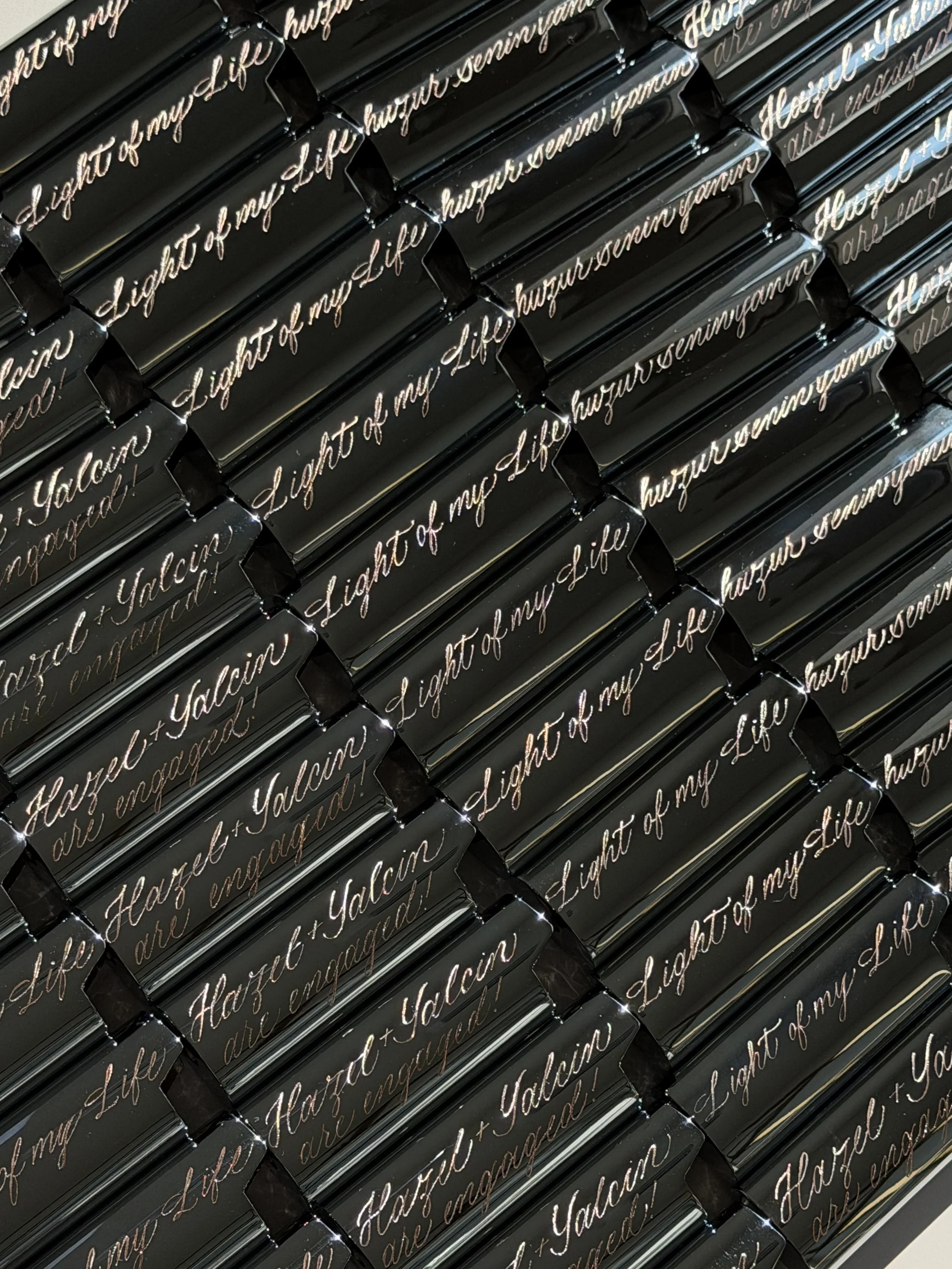 Custom engraved black lighter cases with cursive phrases for an engagement party.