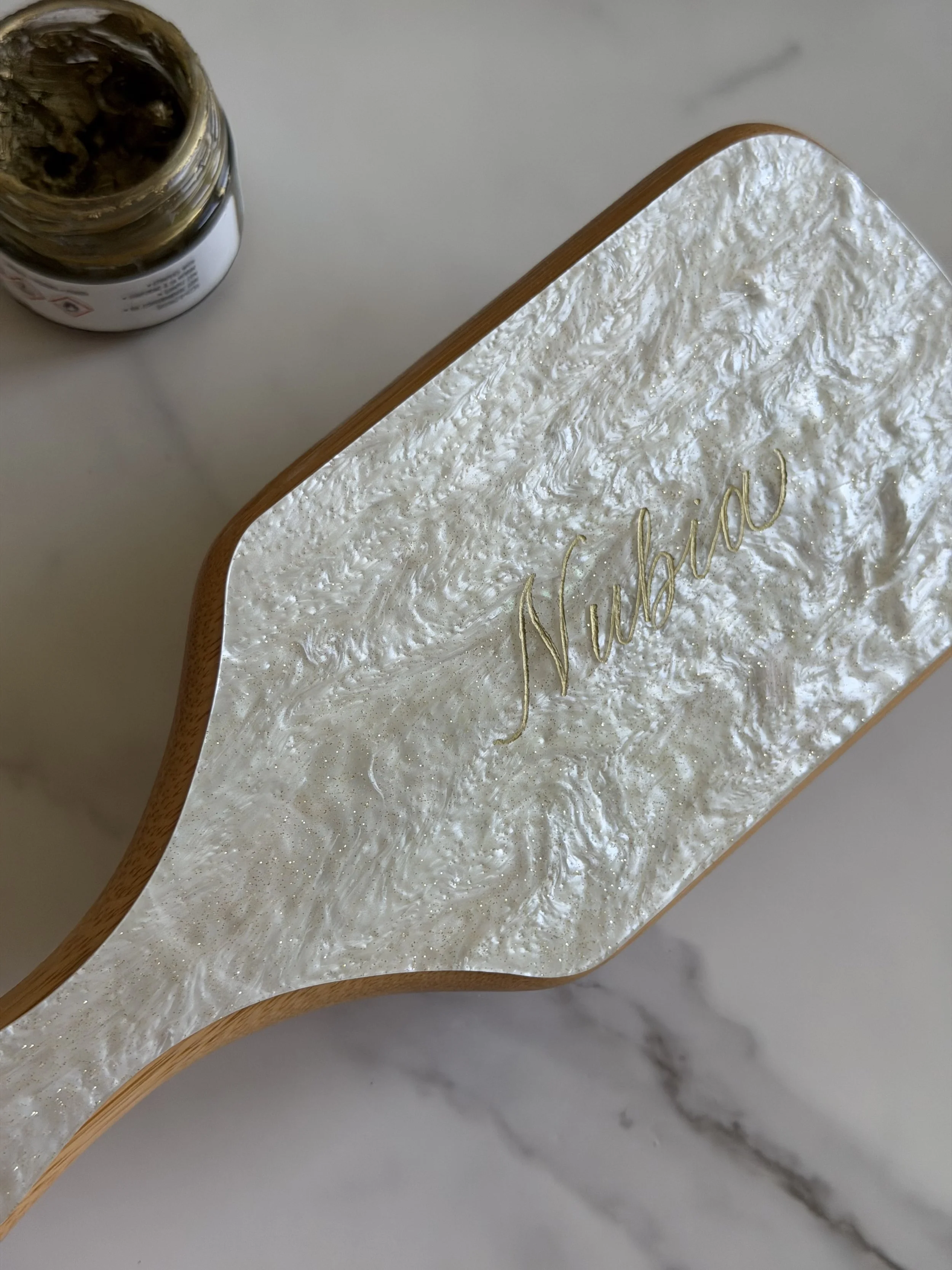 Pearl hairbrush personalized with a name in gold calligraphy.