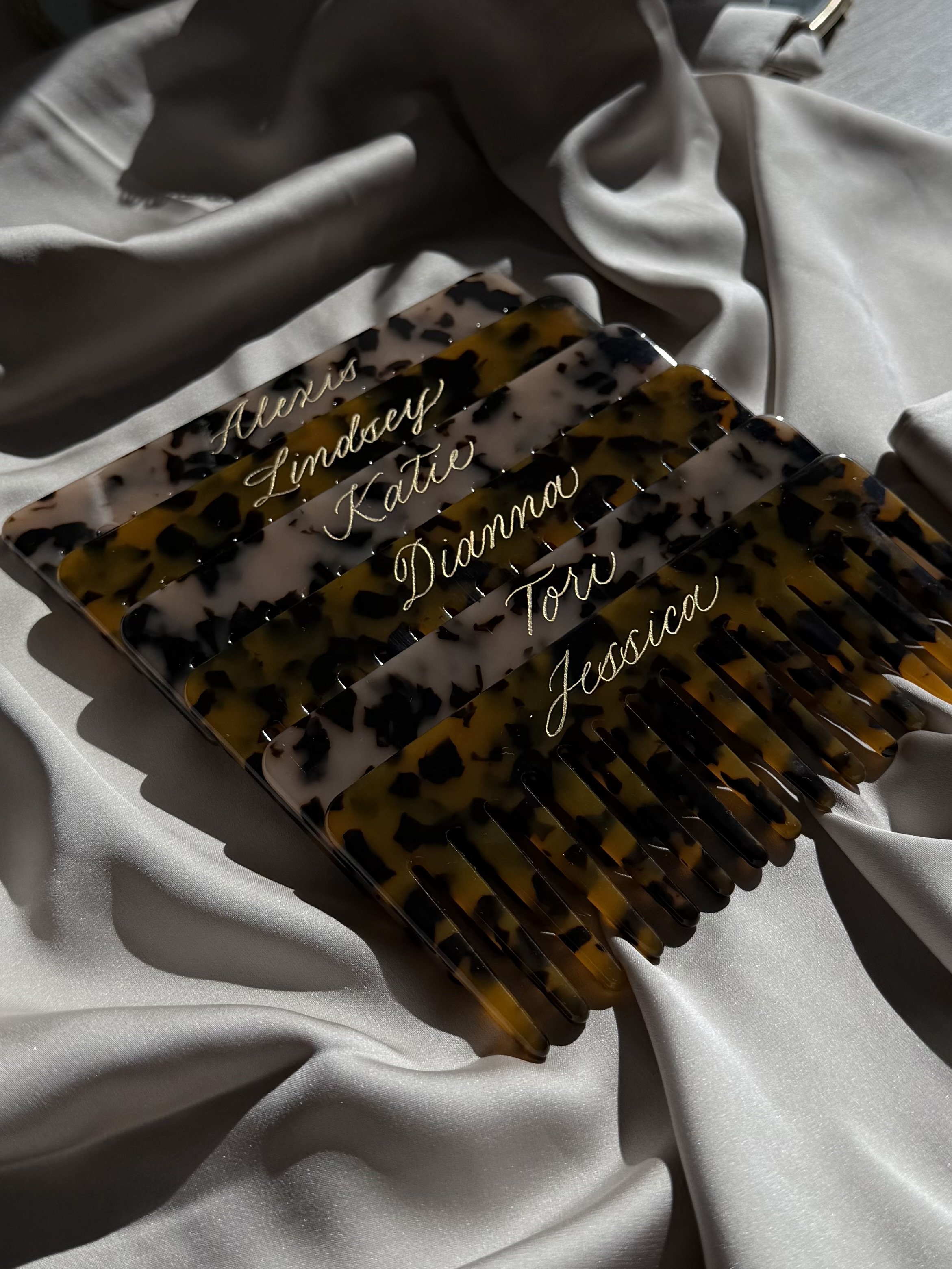 Tortoise claw clips personalized with individual names in gold calligraphy.