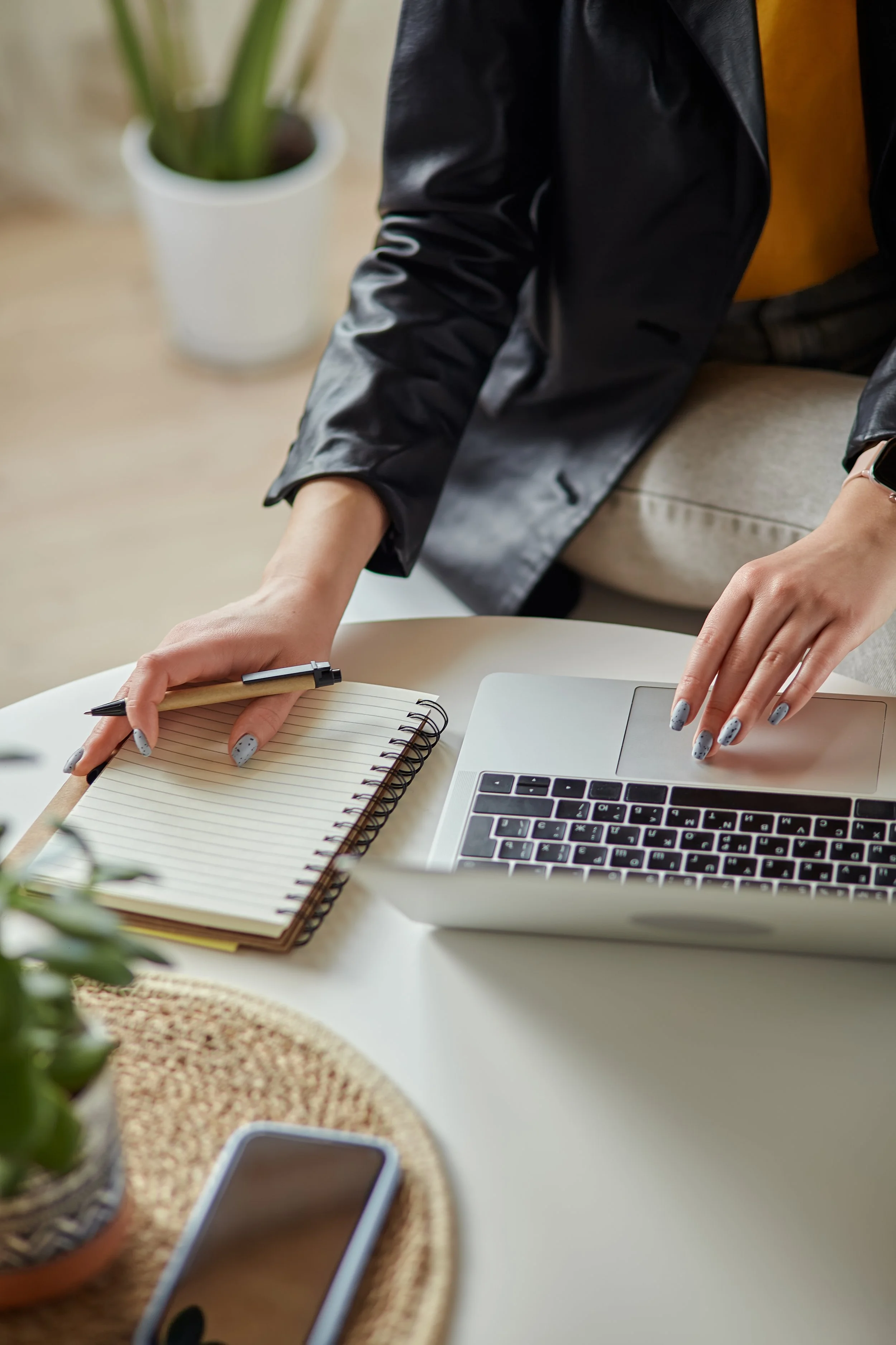 Close up of woman's hands using a laptop and notebook