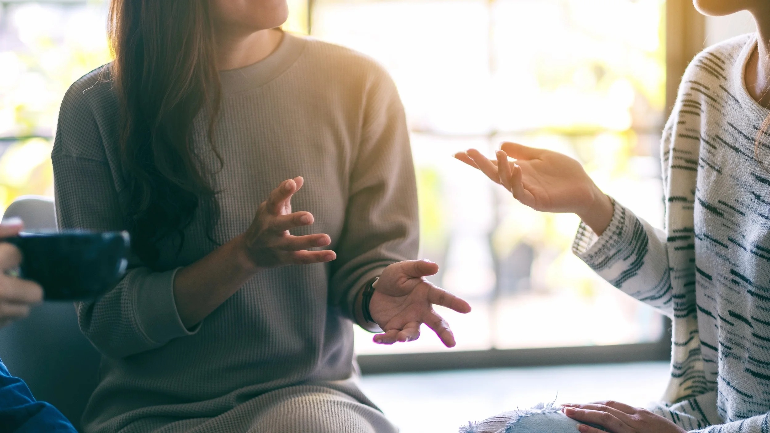 Close up of women in conversation, making hand gestures