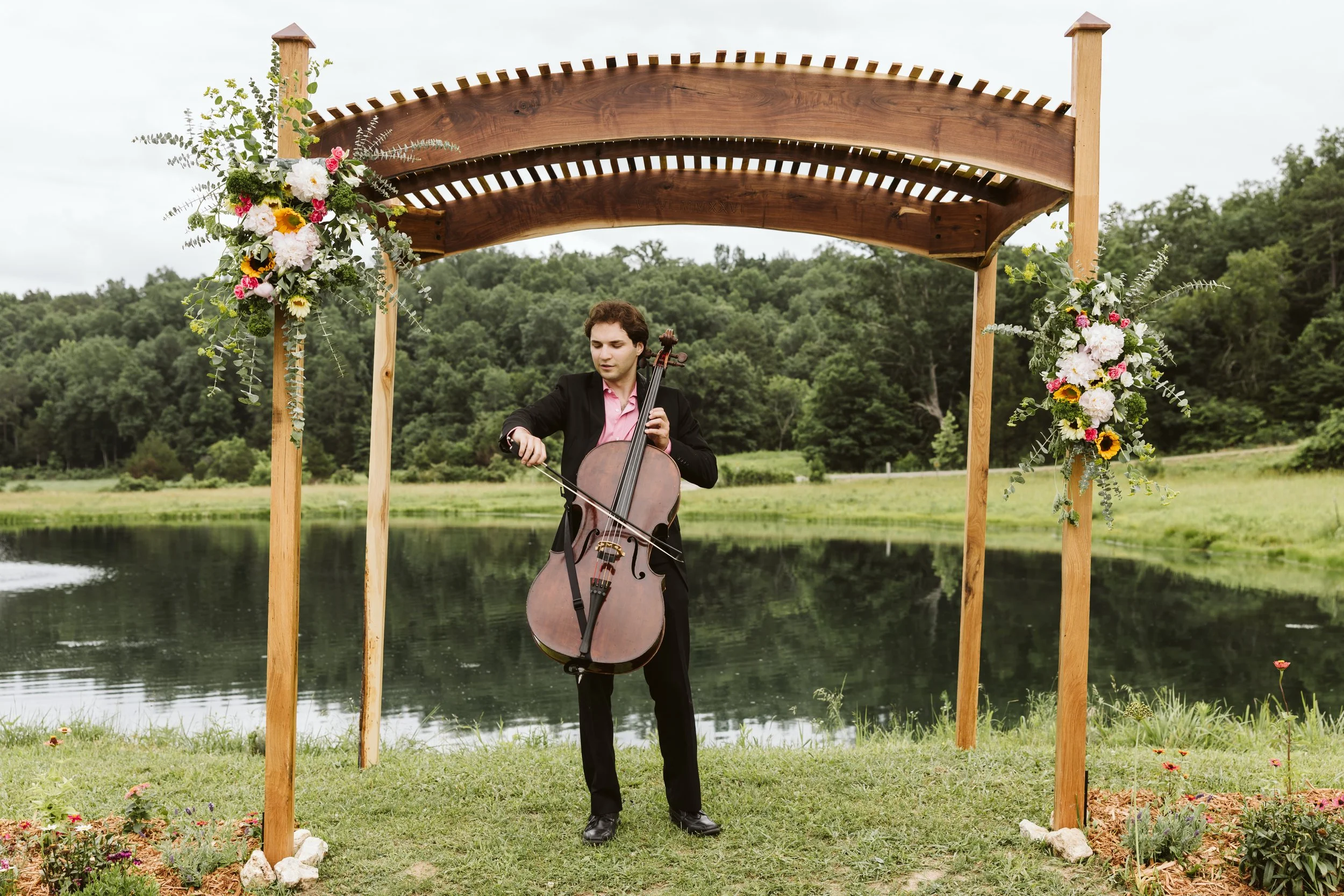 Wedding cellist performing live music underneath the altar at an outdoor wedding ceremony in St. Louis.