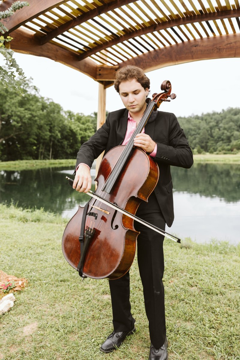 Wedding cellist playing live music under an altar at an outdoor ceremony in St. Louis