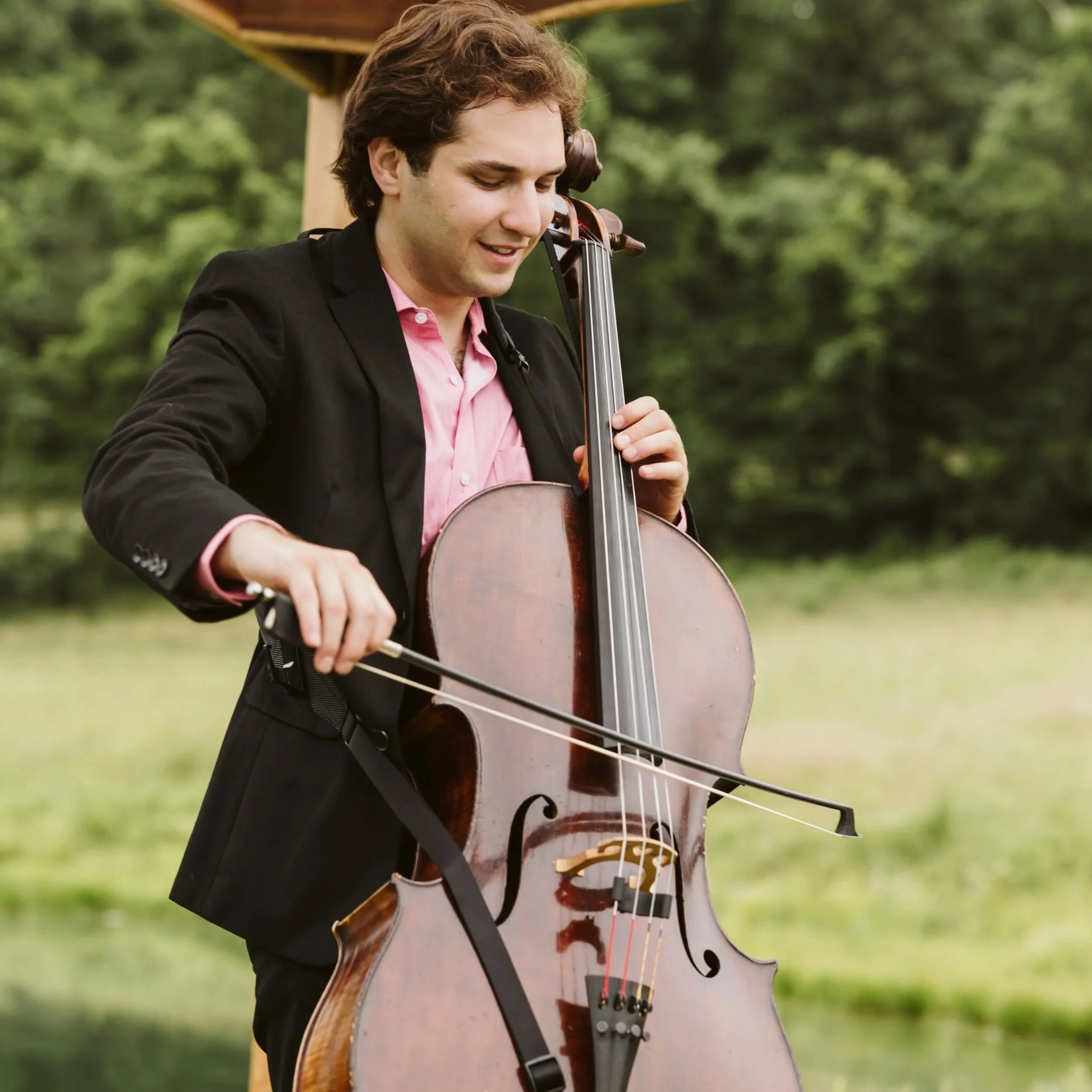 Wedding cellist in a suit providing elegant live music for an outdoor wedding ceremony in St. Louis.