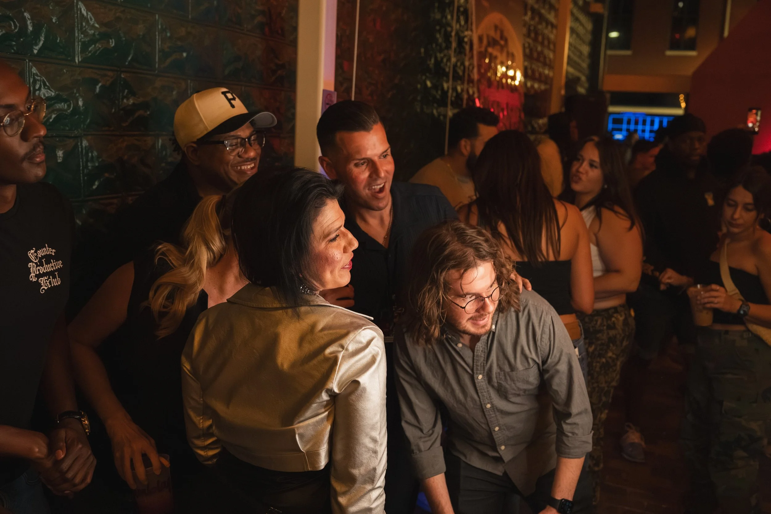 People socializing at a nightclub or bar with dark lighting and red accents.