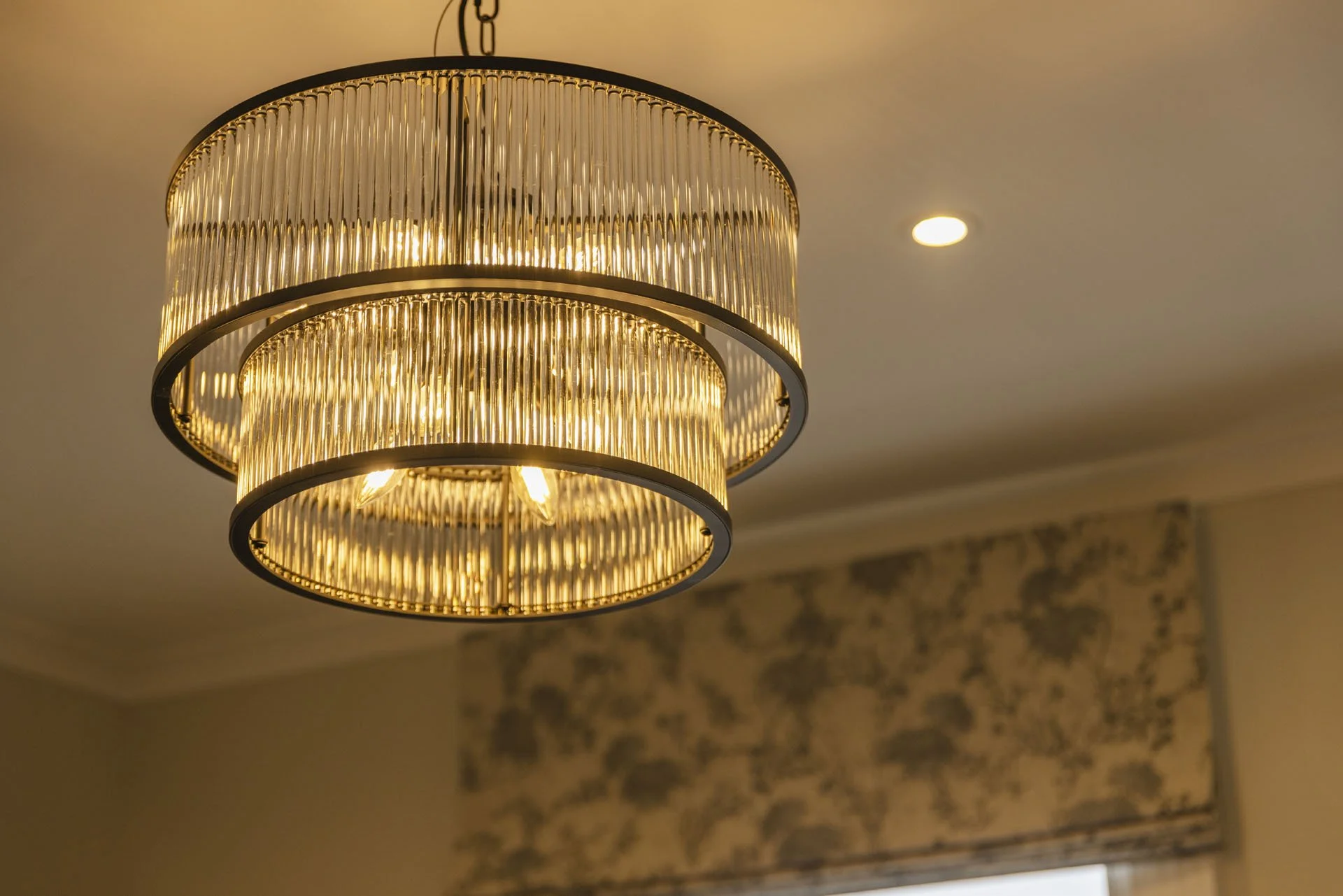 Elegant chandelier with layered rings of glass rods hanging from a ceiling.