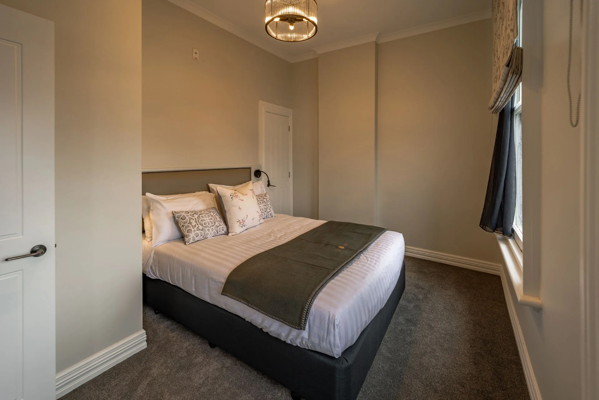 A bedroom with a bed, pillows, and a window with curtains.