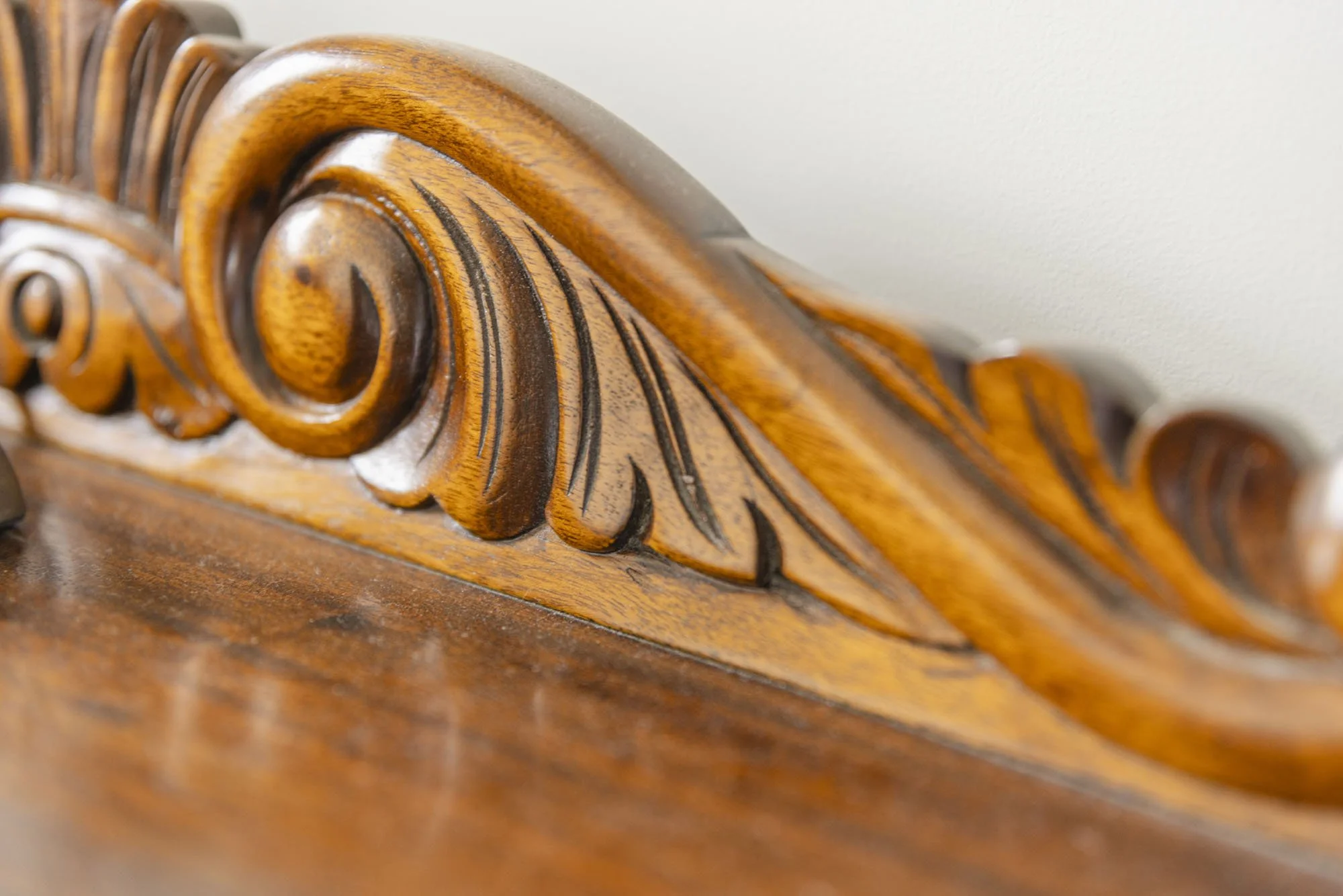 Close-up of a carved wooden furniture piece with scroll and leaf patterns.