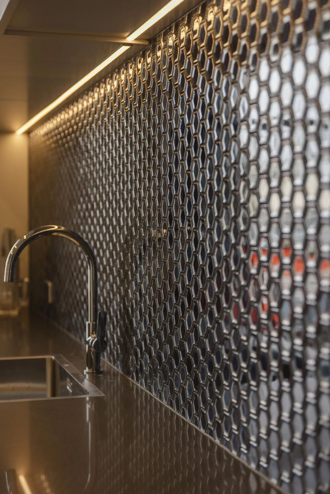 Kitchen with a black geometric tile backsplash, metal faucet, and dark sink.