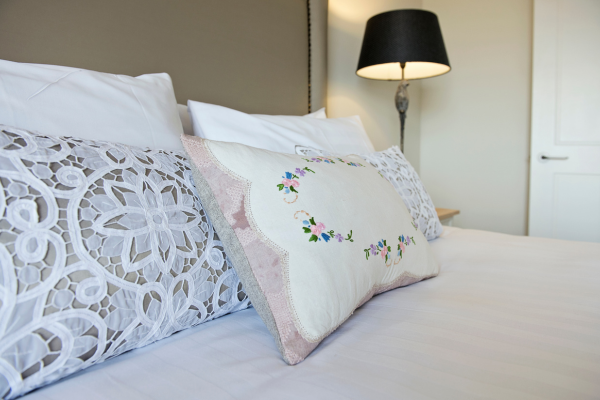 Decorative pillows on a bed with a black bedside lamp and a white door in the background.