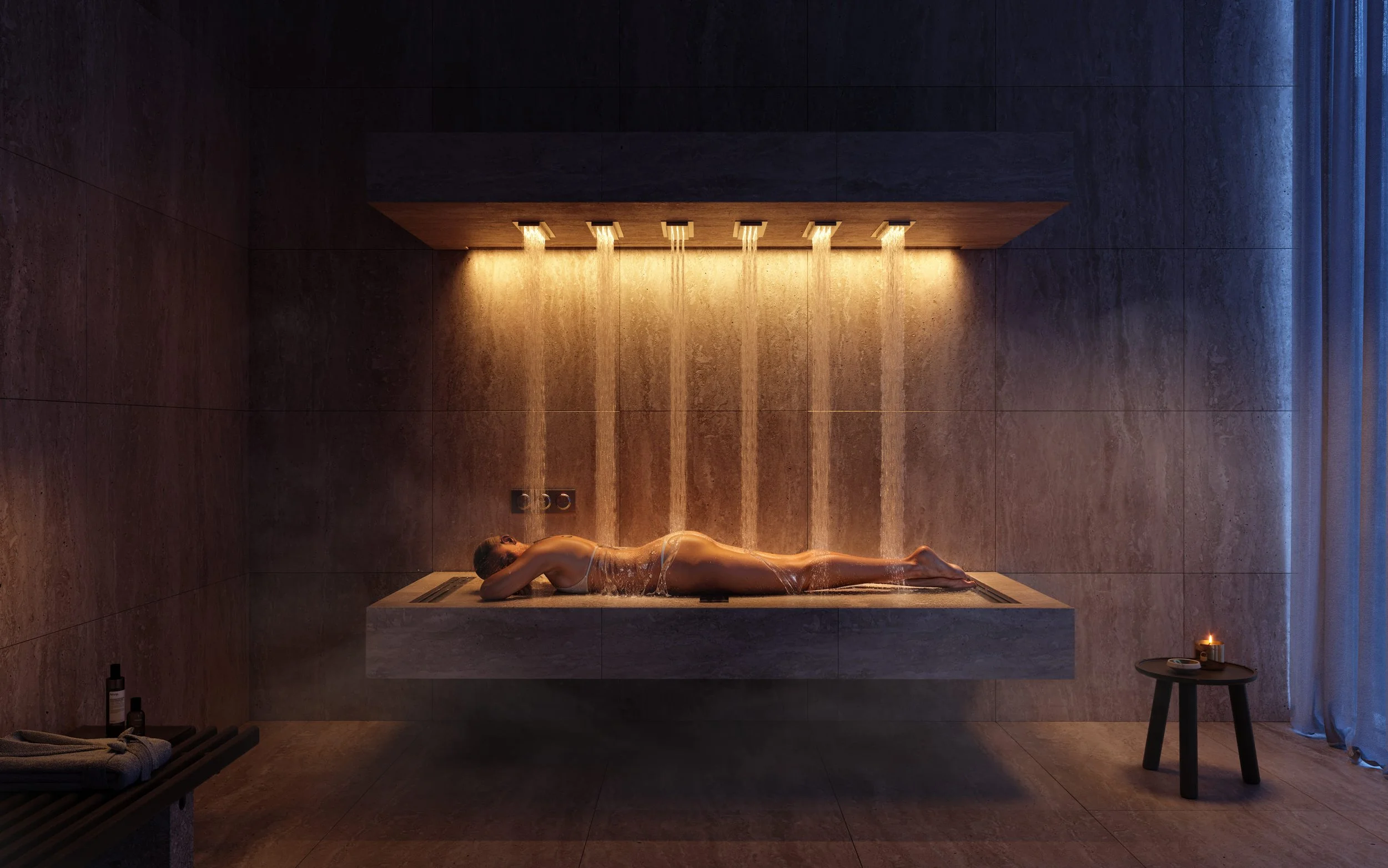 A woman lying on a stone bed under a modern shower with water cascading down from ceiling fixtures in a dimly lit spa room.