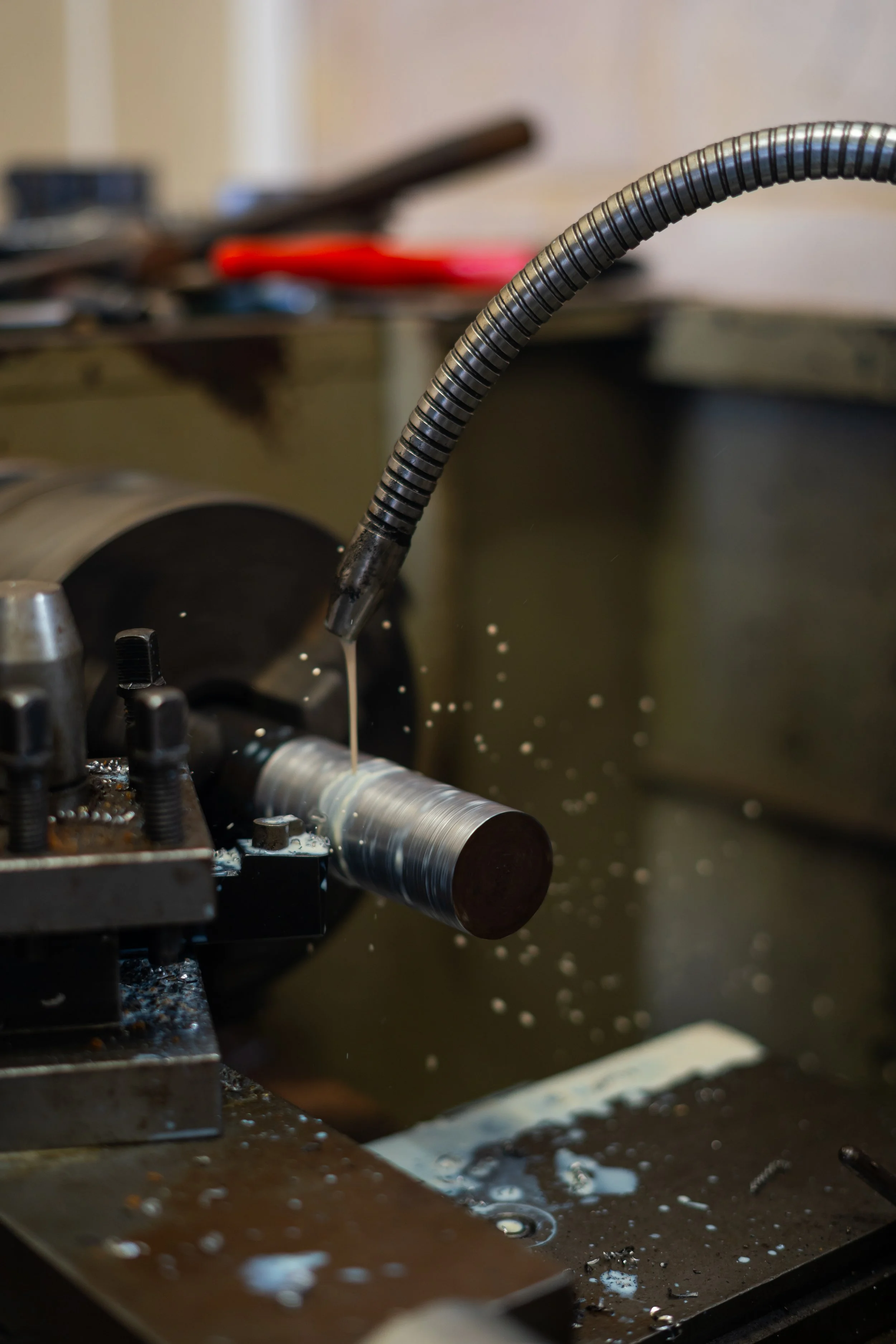 Close-up of a machine drill or mill in a factory or workshop, with metal shavings and oil around it.