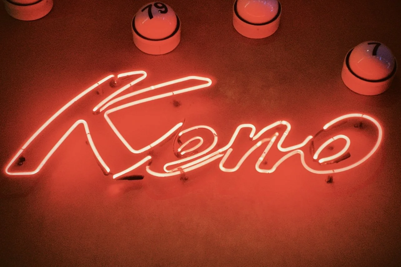 Red neon sign that says 'Keno' in cursive, with several round bingo-style number balls above it.