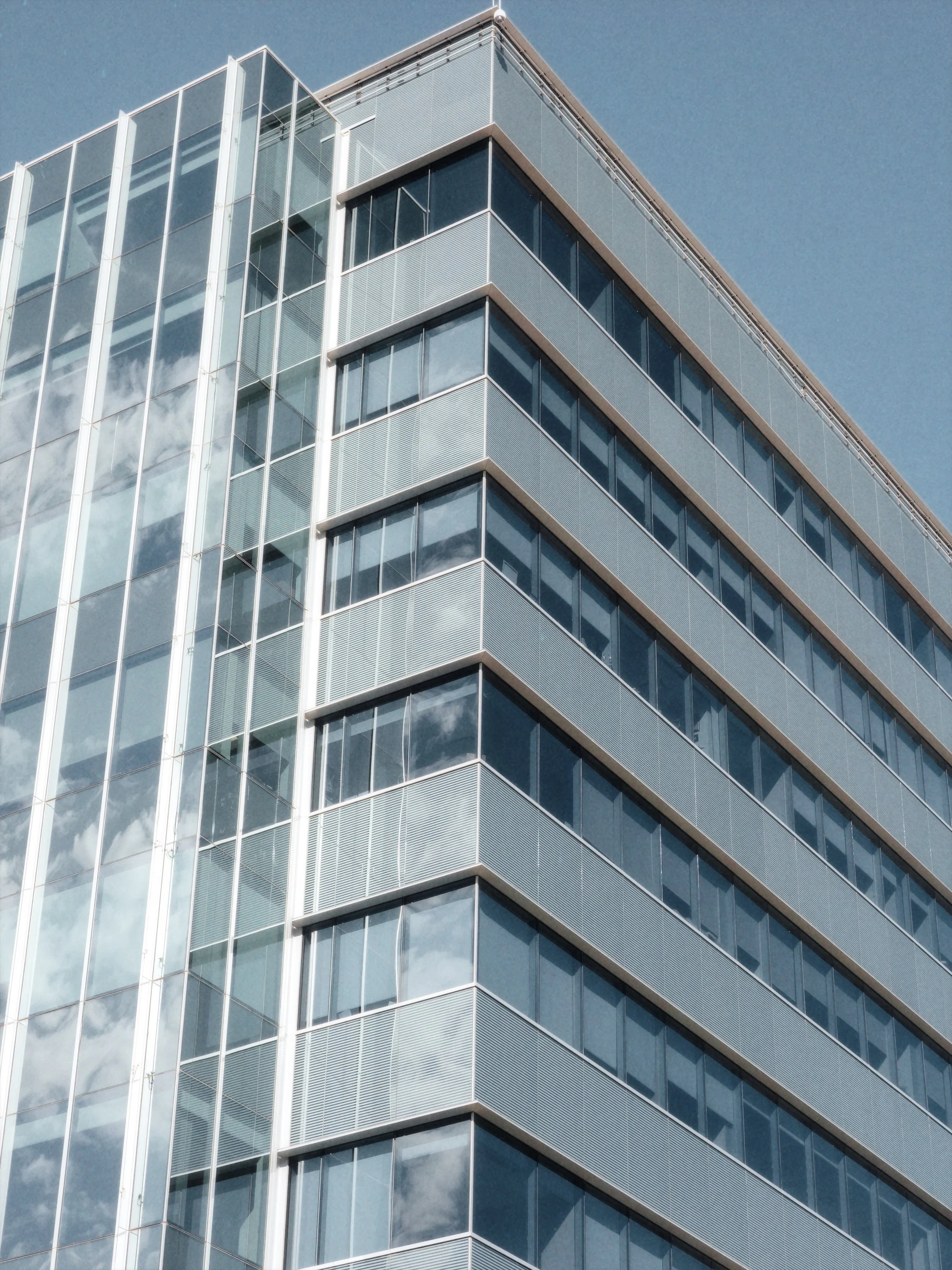 Modern glass office building with reflective windows and blue sky.