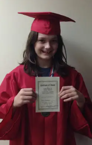 Young girl in a red graduation cap and gown holding a diploma. She is a Vision Therapy graduate from Superior Eye Health.
