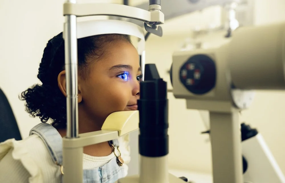 Young girl undergoing an eye examination with an ophthalmic device.