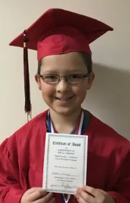 Young child in red graduation gown and cap holding a diploma. He is a Vision Therapy graduate from Superior Eye Health.