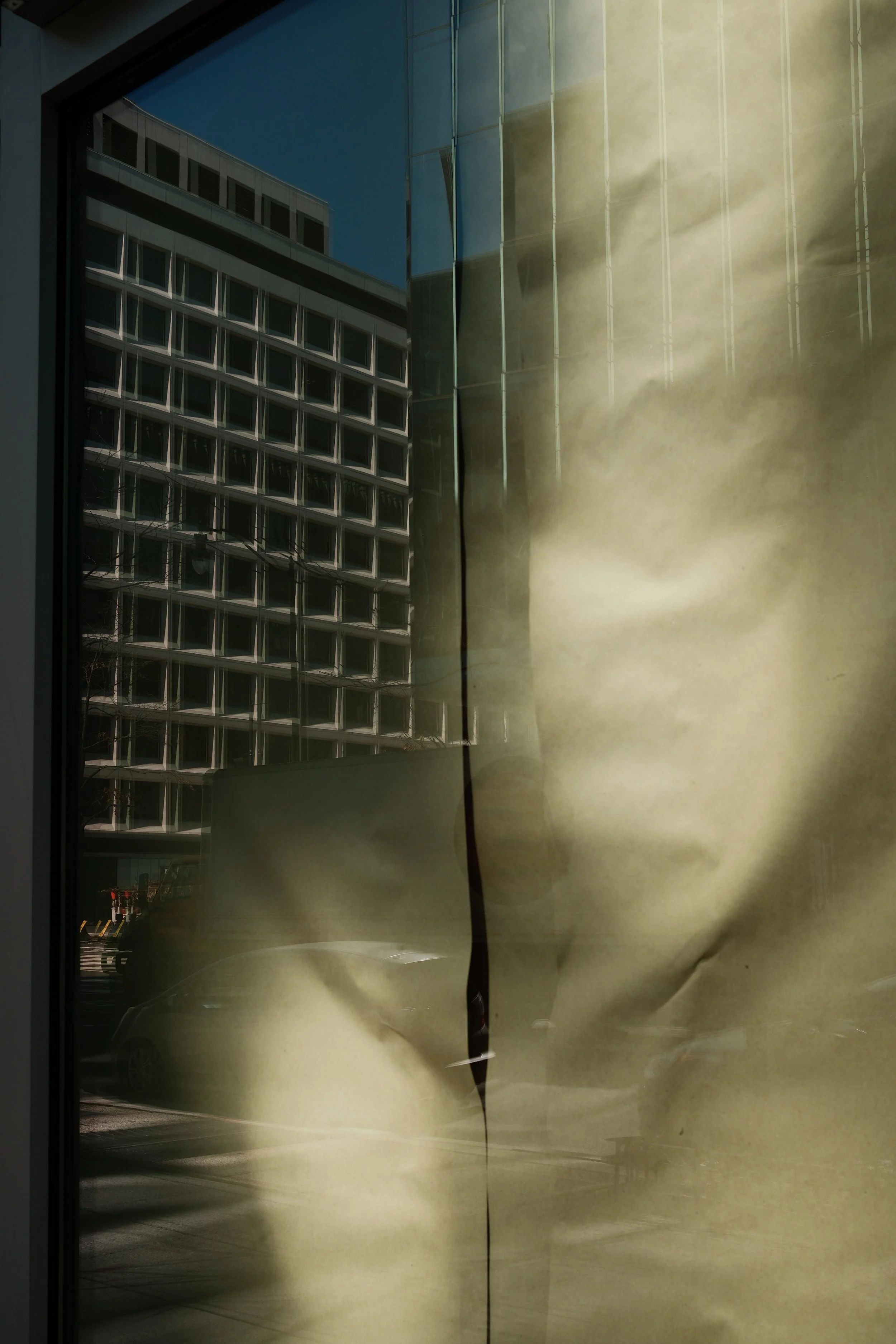 Reflected cityscape seen through a glass window with a torn yellowish paper overlay