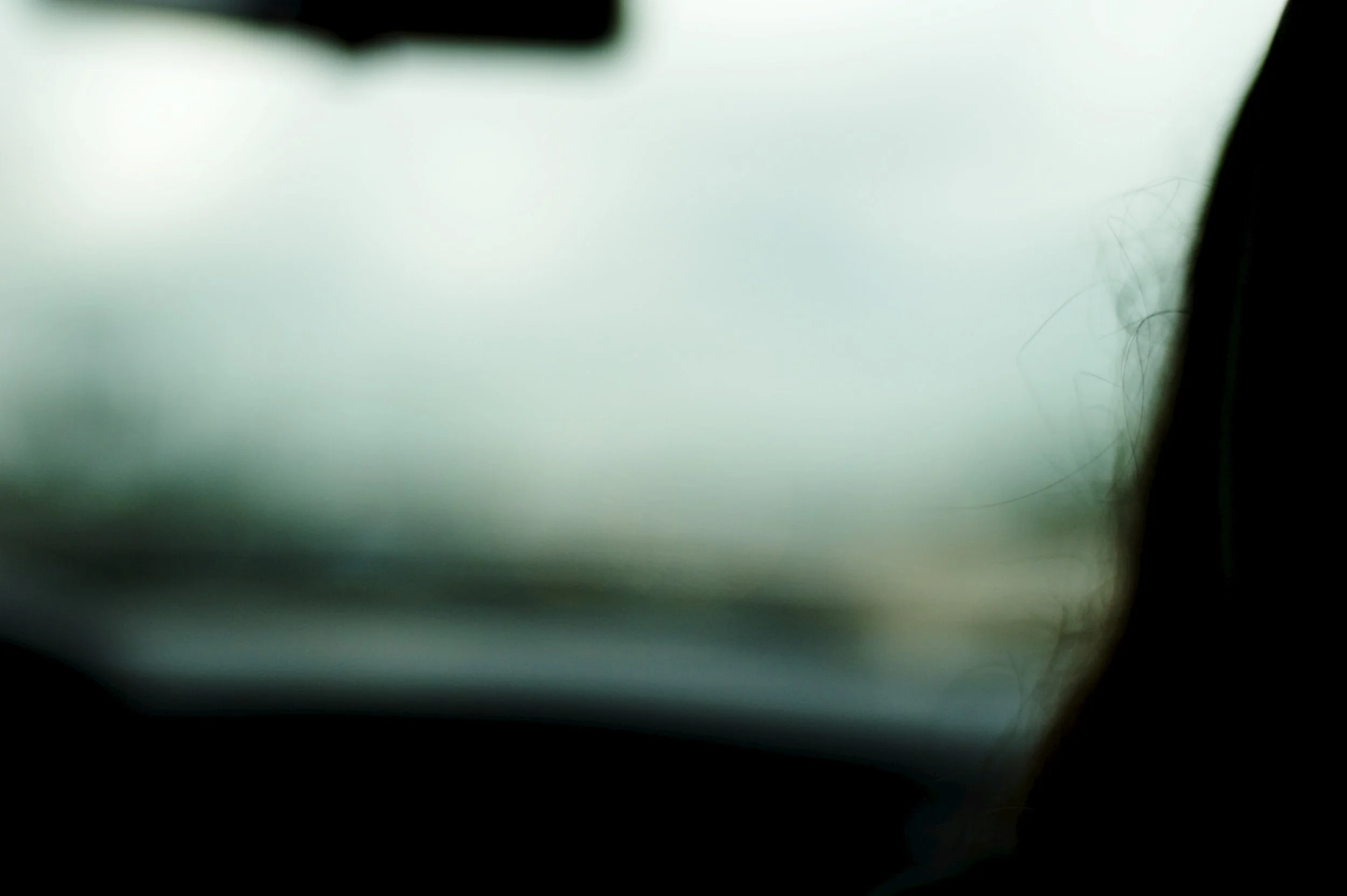 Blurry photo of what appears to be a window with foggy or unclear view, and part of a person's hair visible on the right side