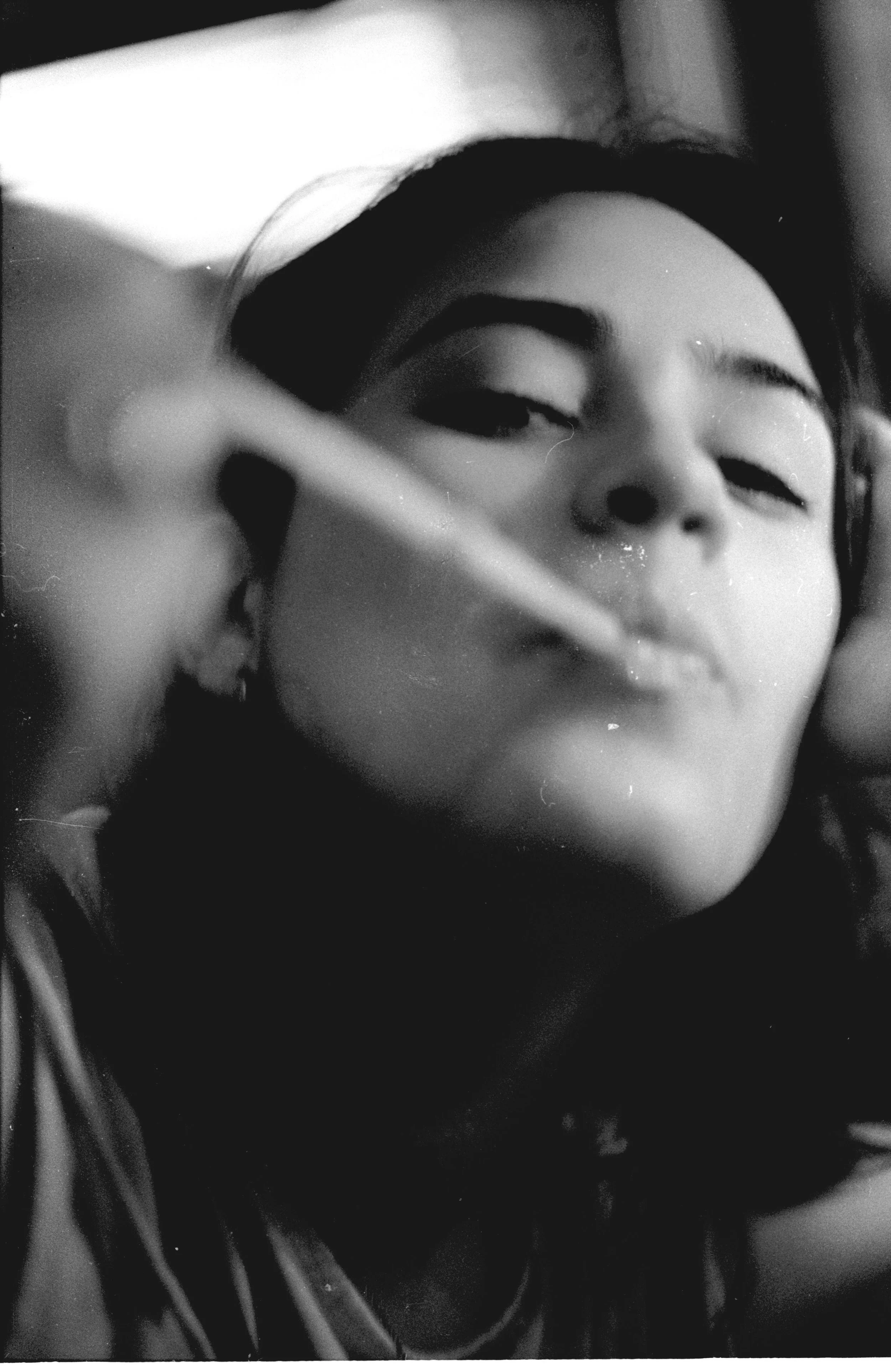 Young woman with dark hair taking a close-up selfie in black and white, with a straw near her lips.