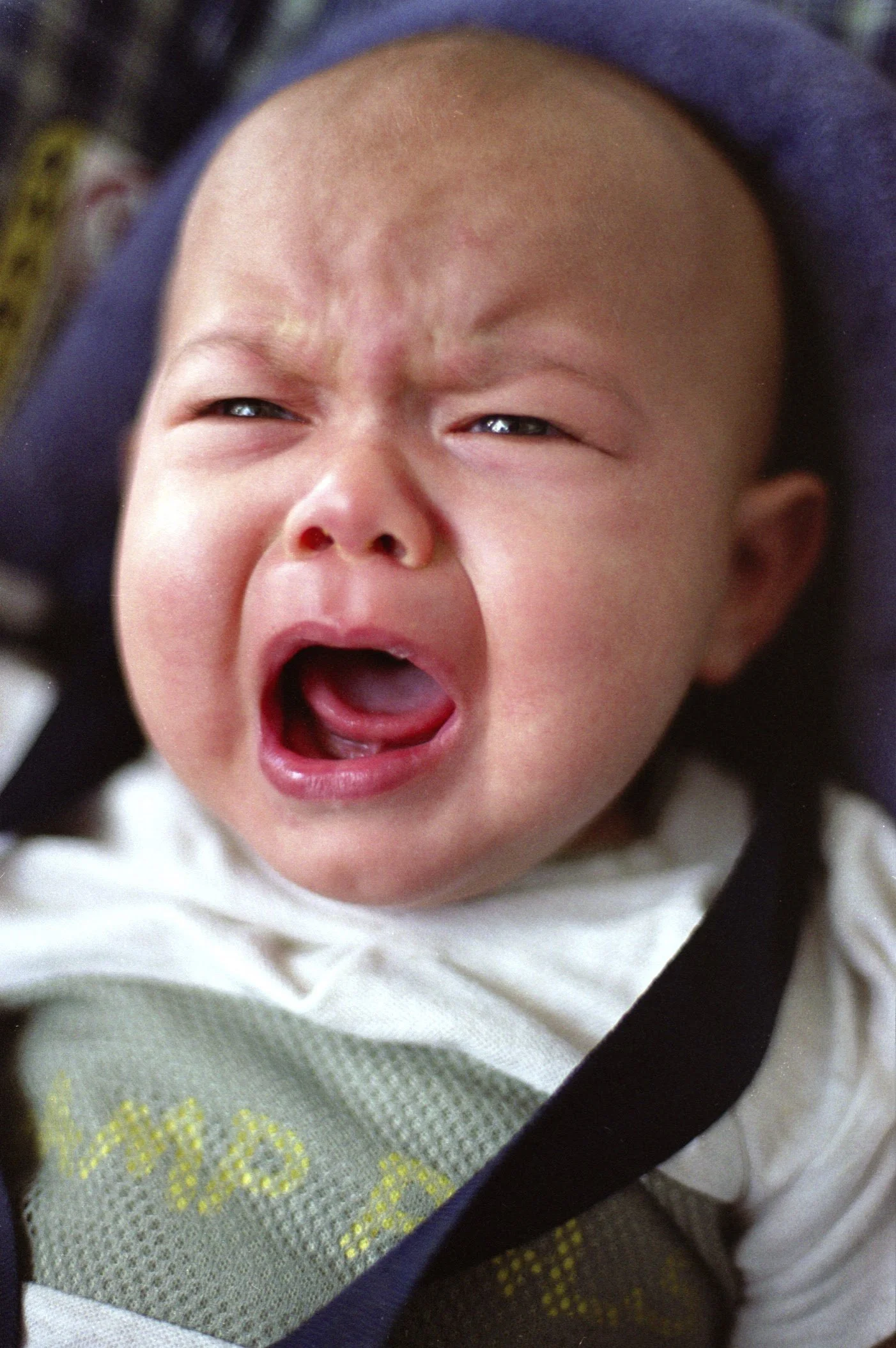 A baby crying with a distressed expression, mouth open, and eyes squinted.