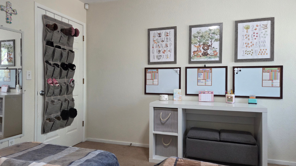 Kids shared bedroom with desk workspace, storage ottoman, and hanging door organizer for extra storage in a small shared space.