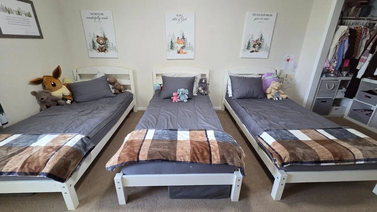 Small shared bedroom with three twin beds arranged to maximize the available floor space.