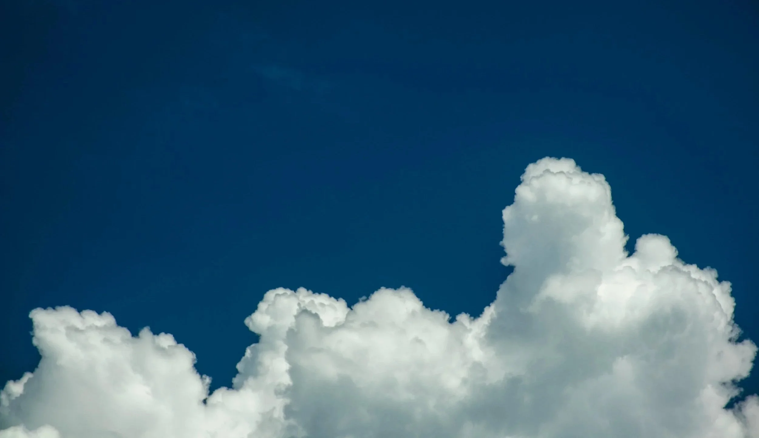 White fluffy clouds against a deep blue sky.