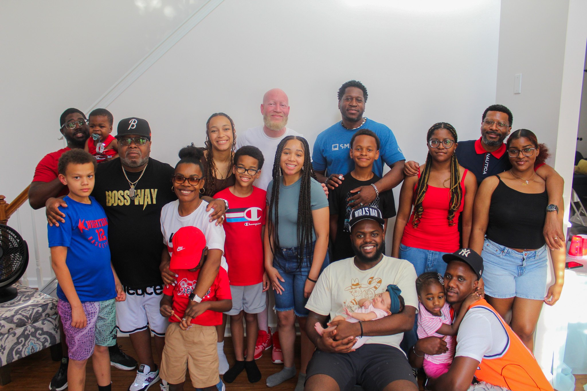 A diverse family and friends group posing together indoors, smiling at the camera.