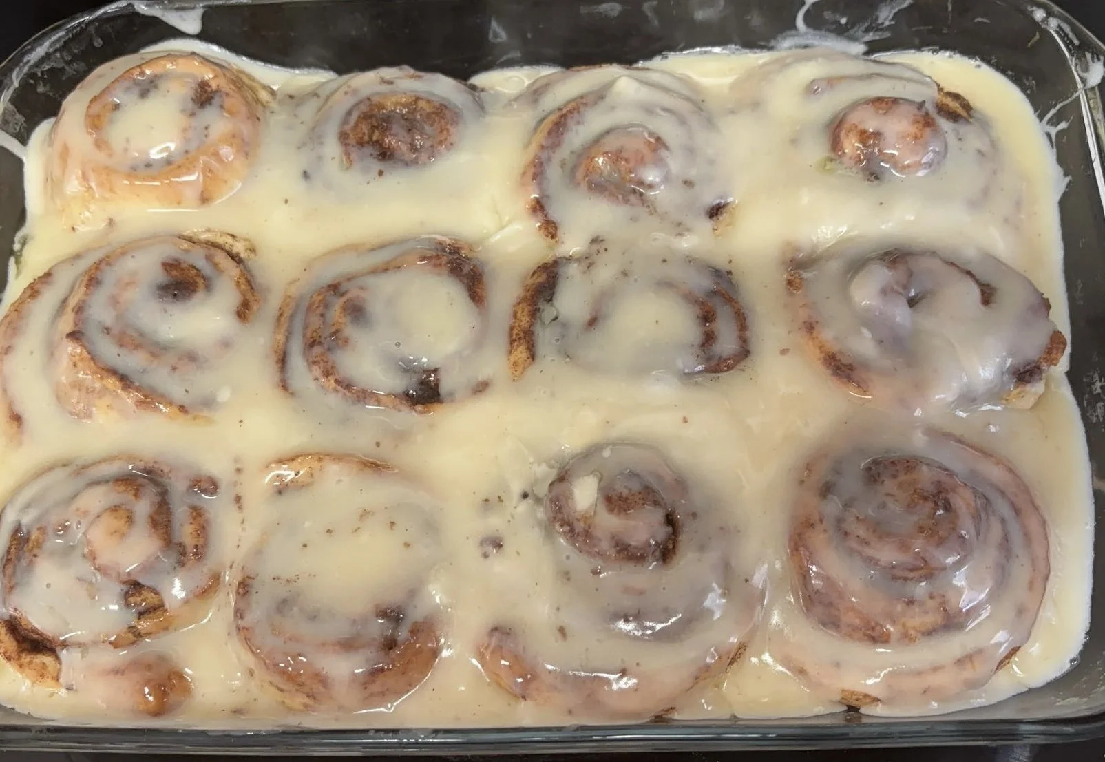 Baked cinnamon rolls with glaze frosting in a baking dish.