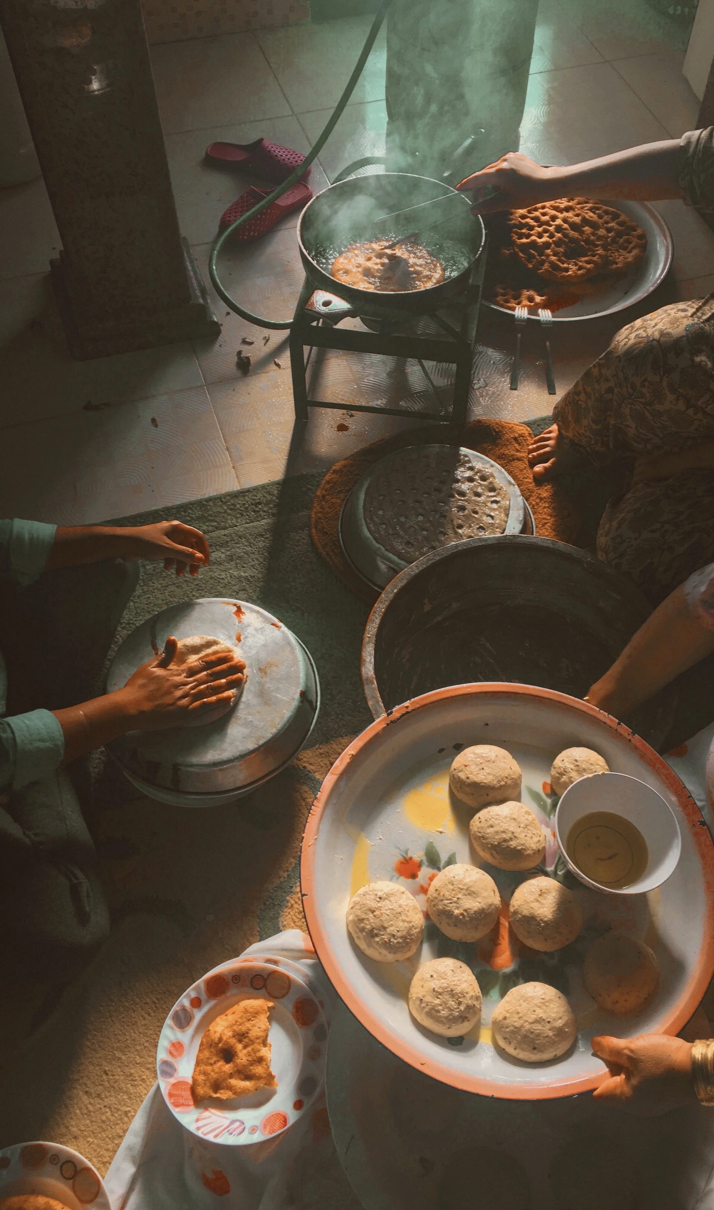 People preparing traditional Jordanian food, with trays of round bread in a kitchen setting.