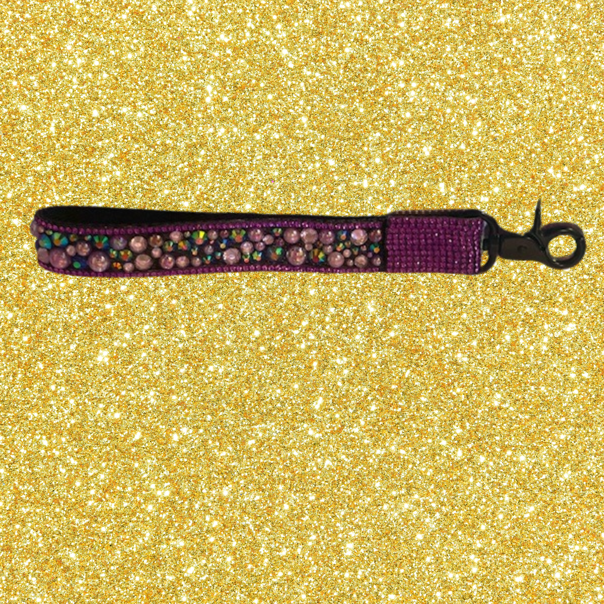 A purple dog collar with pink rhinestones and multicolored beads lying on a gold glitter background.