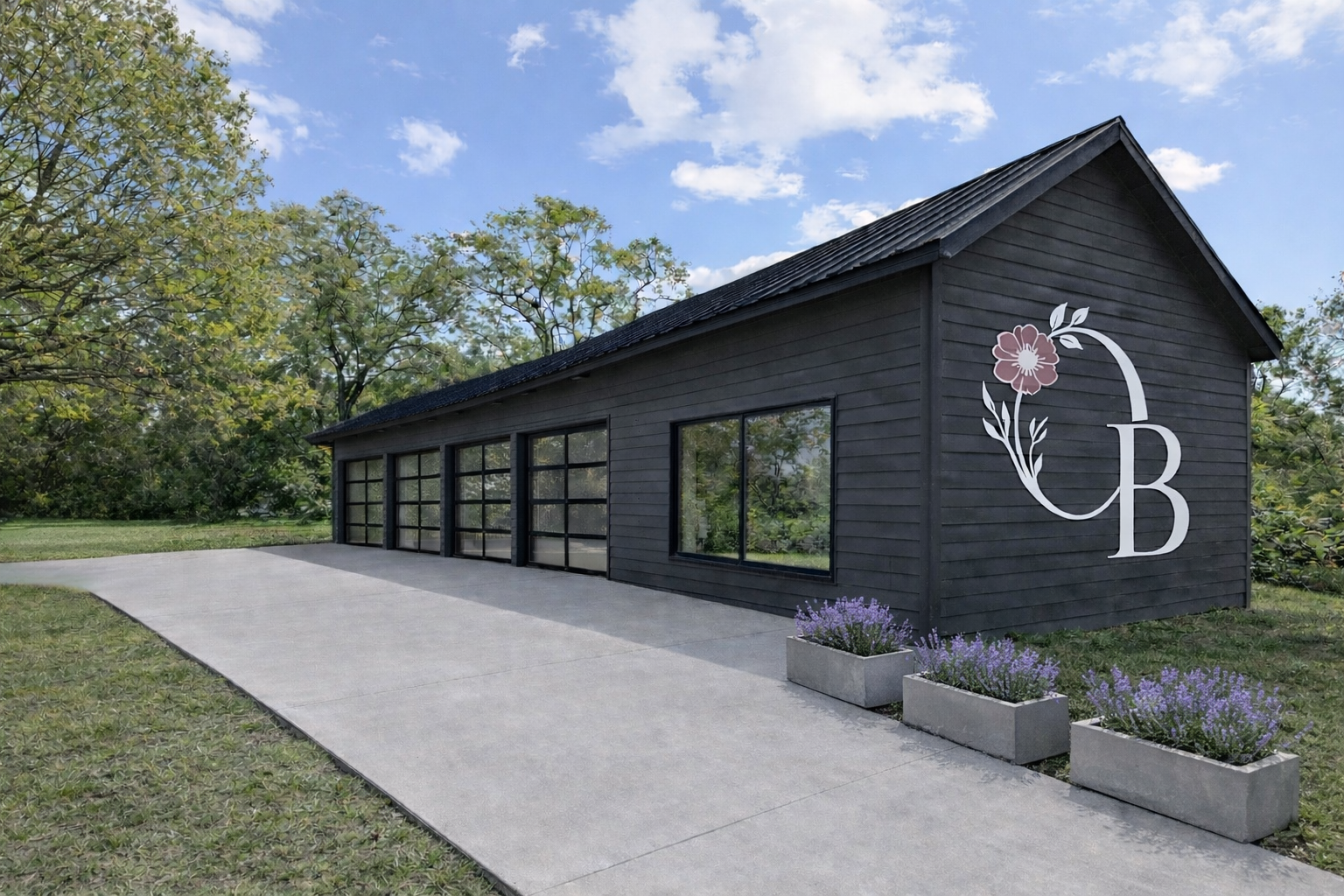 A black garage with large windows, gray concrete driveway, and three rectangular flower planters with purple flowers. Facing a green lawn with trees, under a partly cloudy sky.