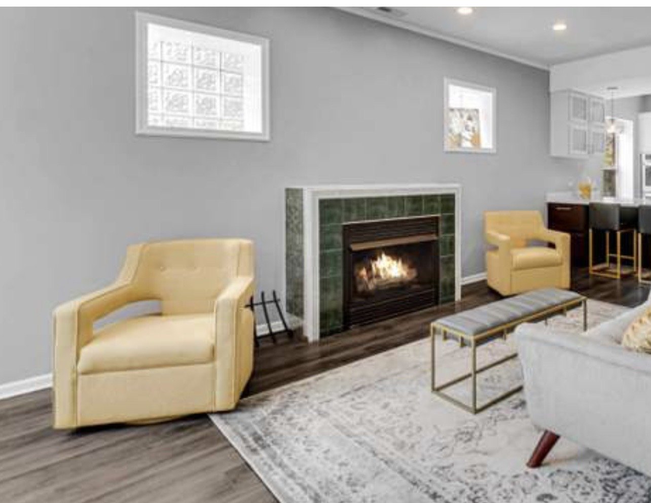 Living room with a yellow armchair, a fireplace, and a white sofa on a patterned rug.