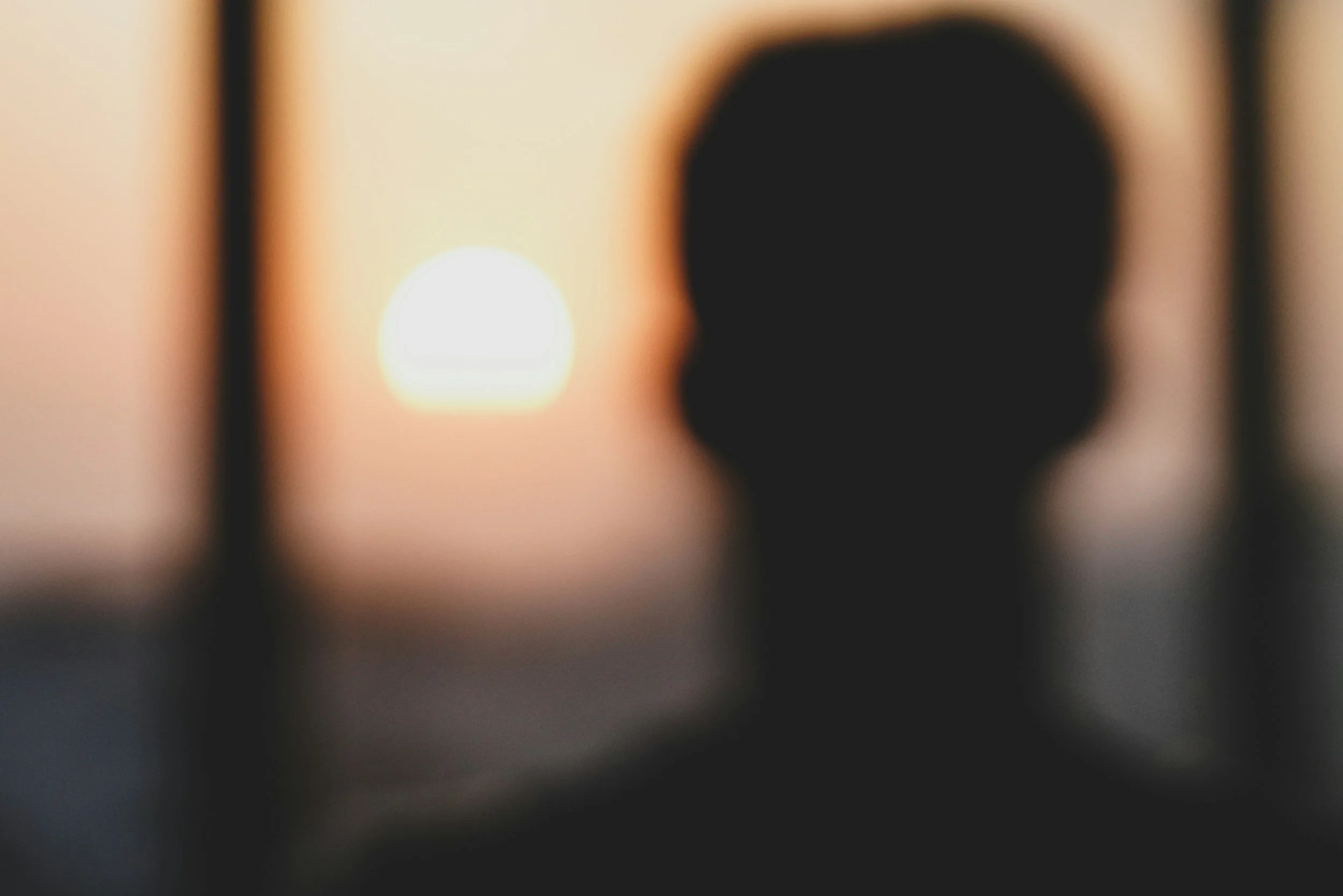 Silhouette of a person looking at a sunset through a window as an image placeholder