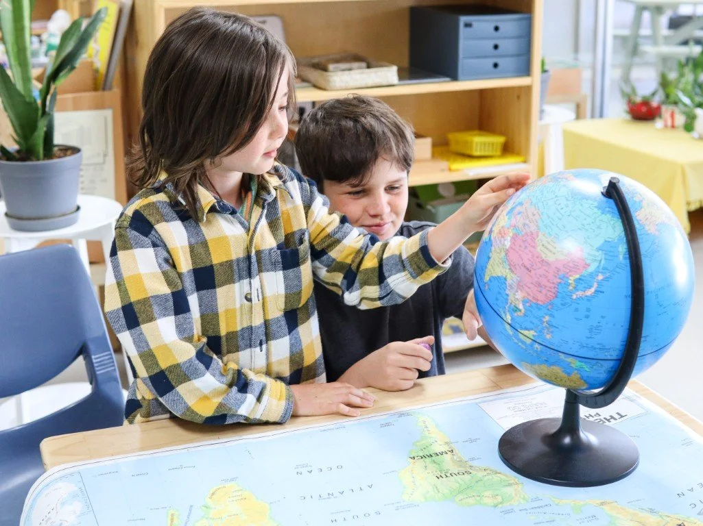 Two Upper Primary children examining a globe on a table in a classroom at our Port Kennedy Primary School.